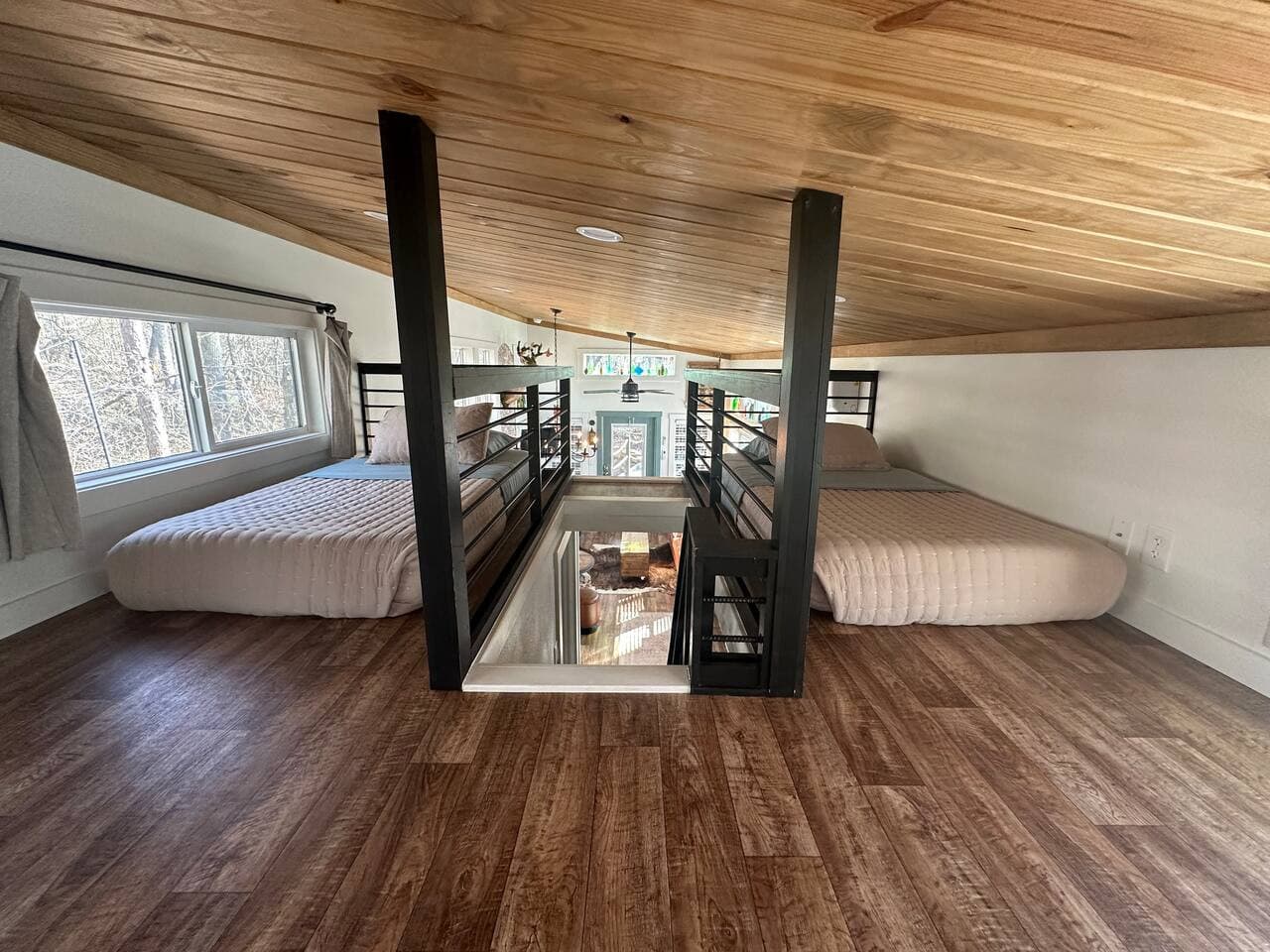 The loft, with views of the creek, features two twin beds and a cozy sitting area with floor chairs and a butterfly table—an inviting hideaway perfect for kids.