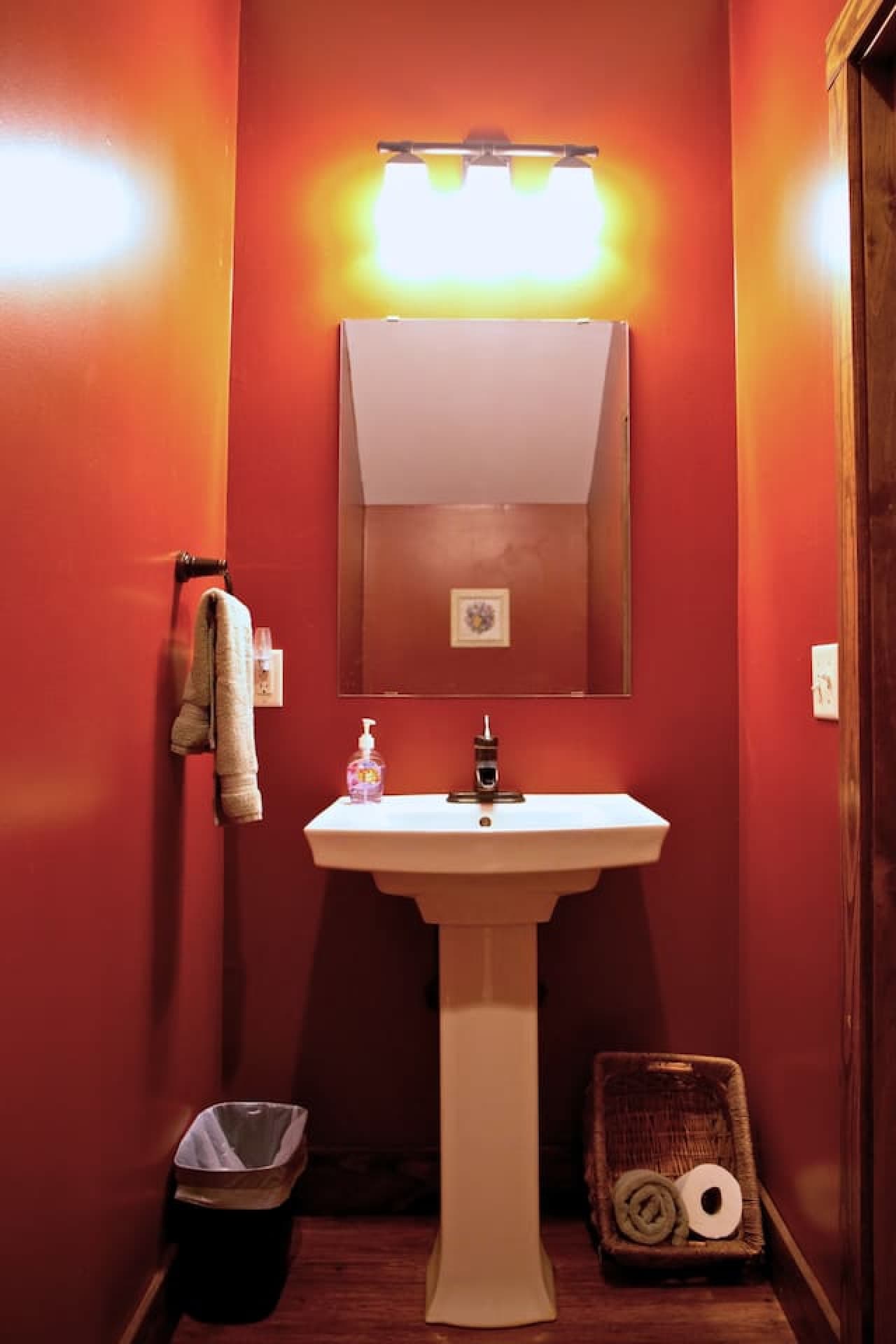 The half bath, located across from the kitchen, includes a pedestal sink and toilet.