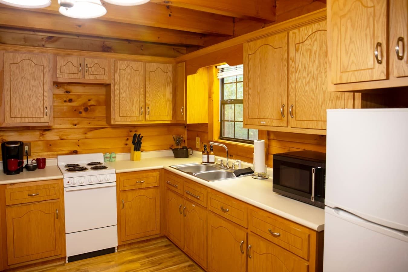 Kitchen with electric stove, oven, microwave, fridge, and Keurig coffee maker for all your culinary needs.