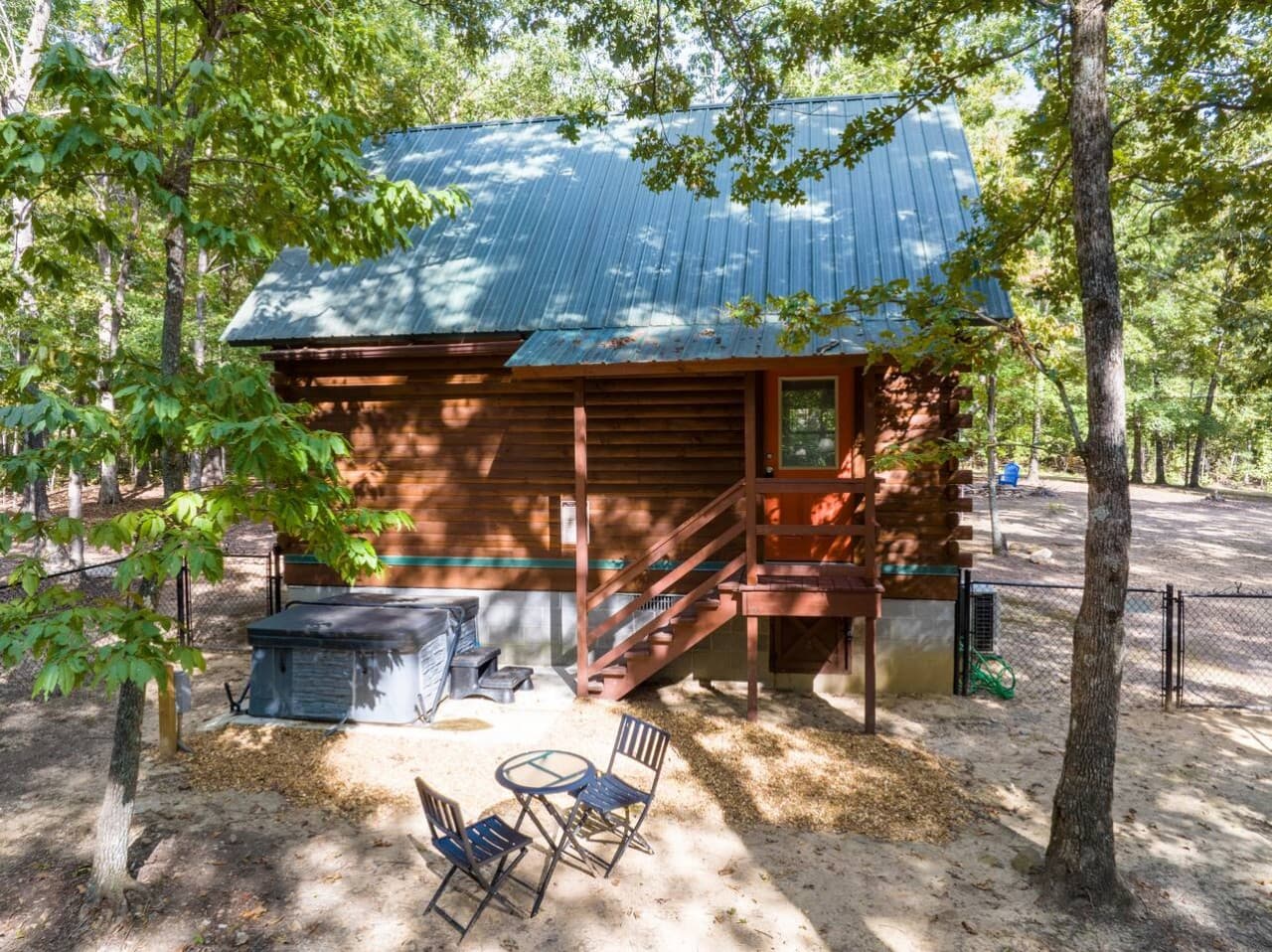 Back of Walden Cabin featuring a hot tub, outdoor dining area, and a fenced backyard for privacy and relaxation.