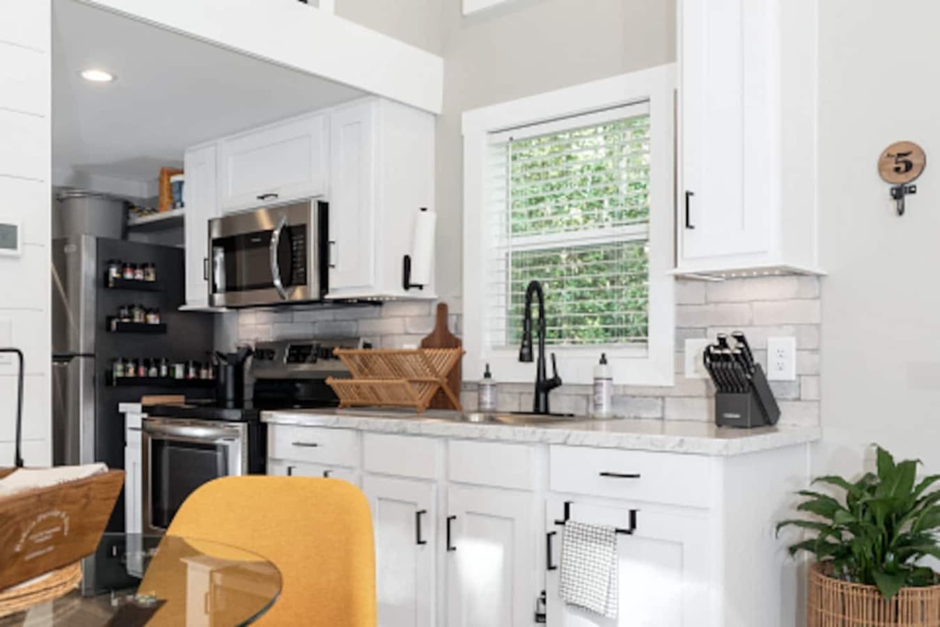 Stylish galley kitchen featuring sleek stainless steel appliances, white cabinets, and a window view that brings in natural light