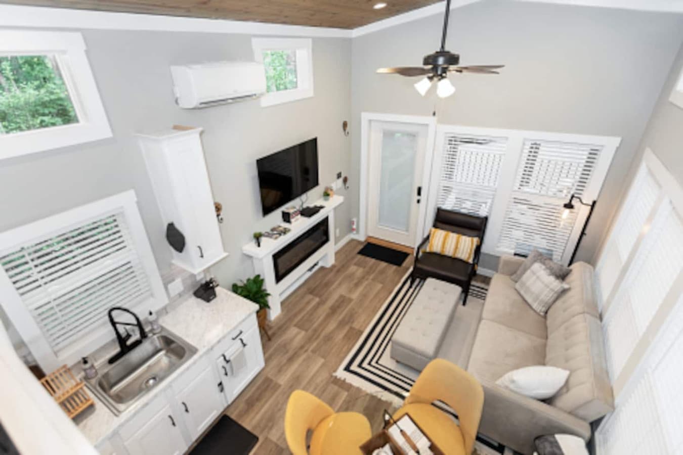 Bright open-concept living area featuring a cozy sofa, electric fireplace, and TV, seamlessly connected to a modern kitchen and dining space for four.