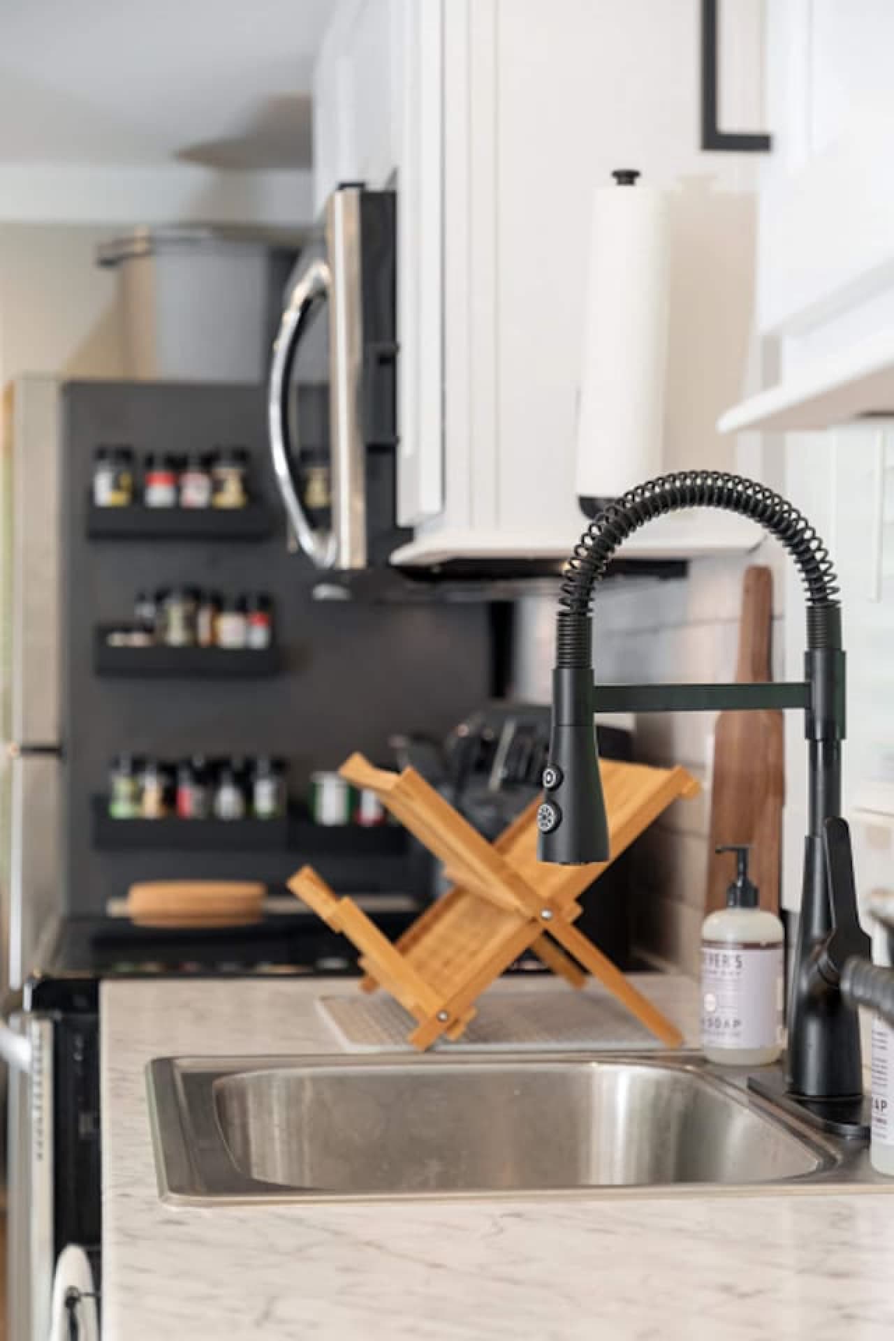 Modern kitchen setup featuring a deep sink with a pull-down faucet, stainless sink, and a spice rack for convenient cooking.