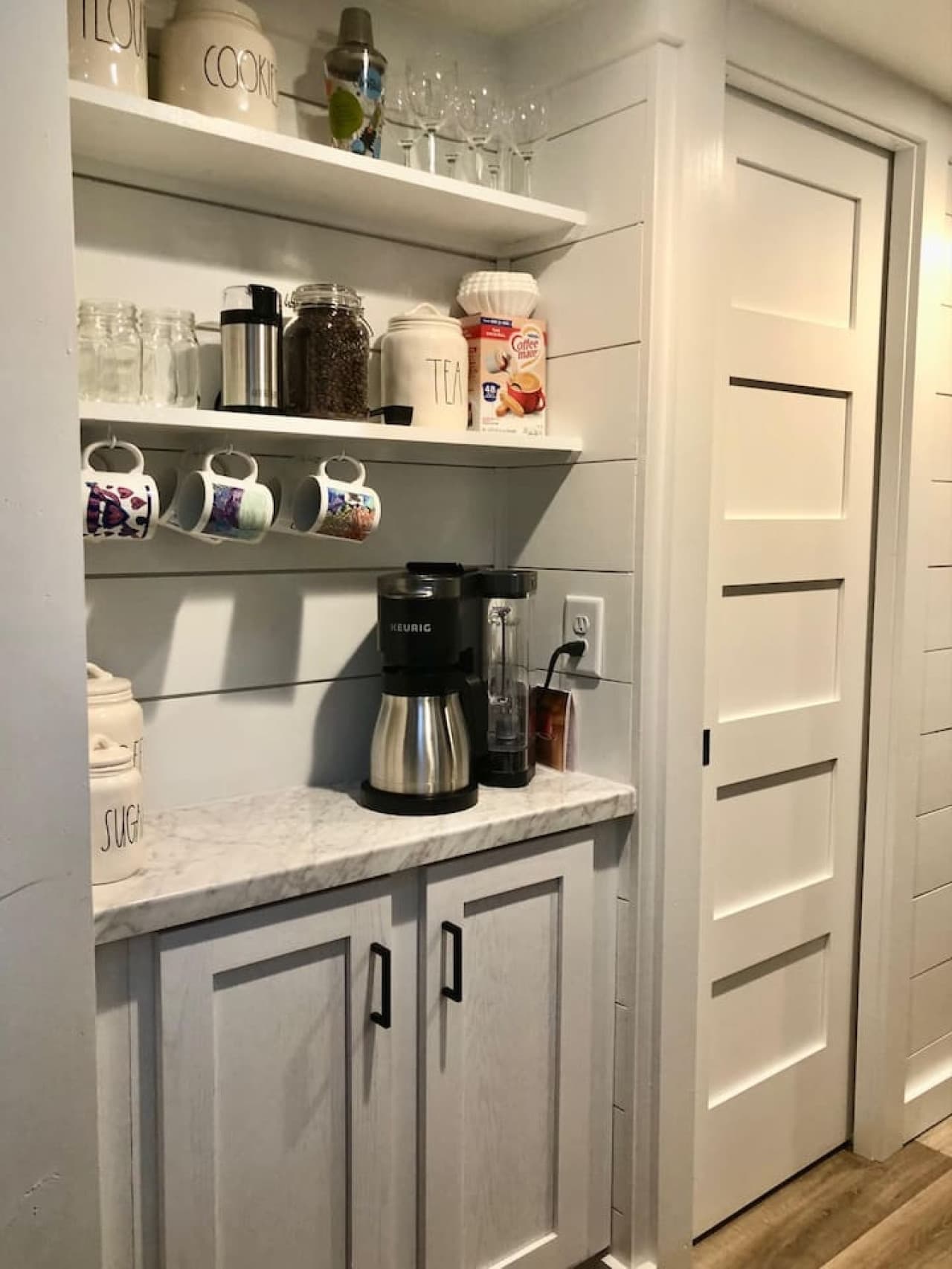 Charming coffee nook with a Keurig, drip coffee maker, and open shelving stocked with mugs, jars, and essentials for your morning brew.