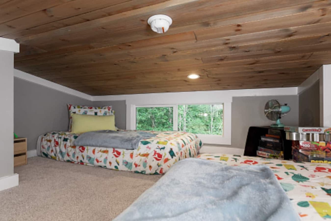 Loft space (not walkable) with two twin beds, soft linens, and a collection of games — the perfect hangout spot for kids.
