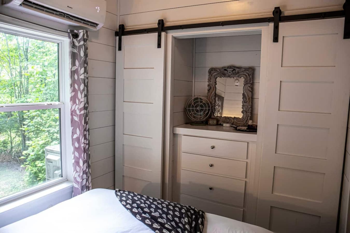 The master bedroom features double barn-door closets and a dresser for plenty of storage.