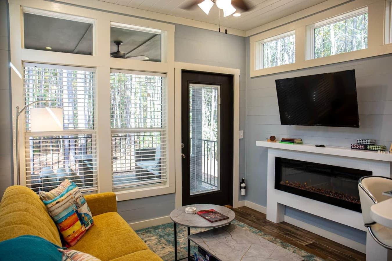 This cozy living space invites you to unwind with its bright, airy atmosphere and peaceful view of the woods.