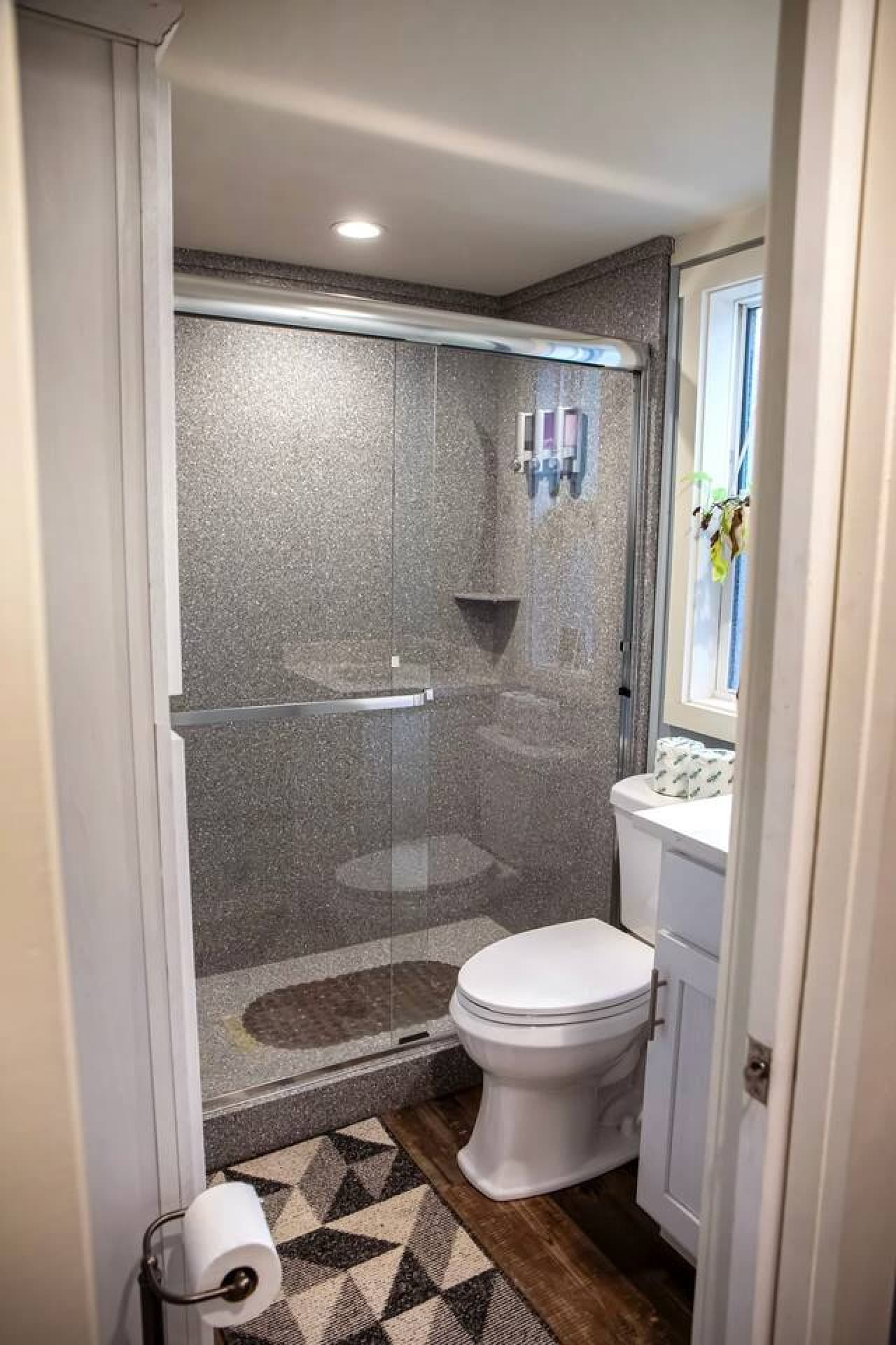 Bathroom is both functional and stylish, featuring a sleek glass shower with a beautiful pebble floor and soft lighting that adds a touch of elegance.