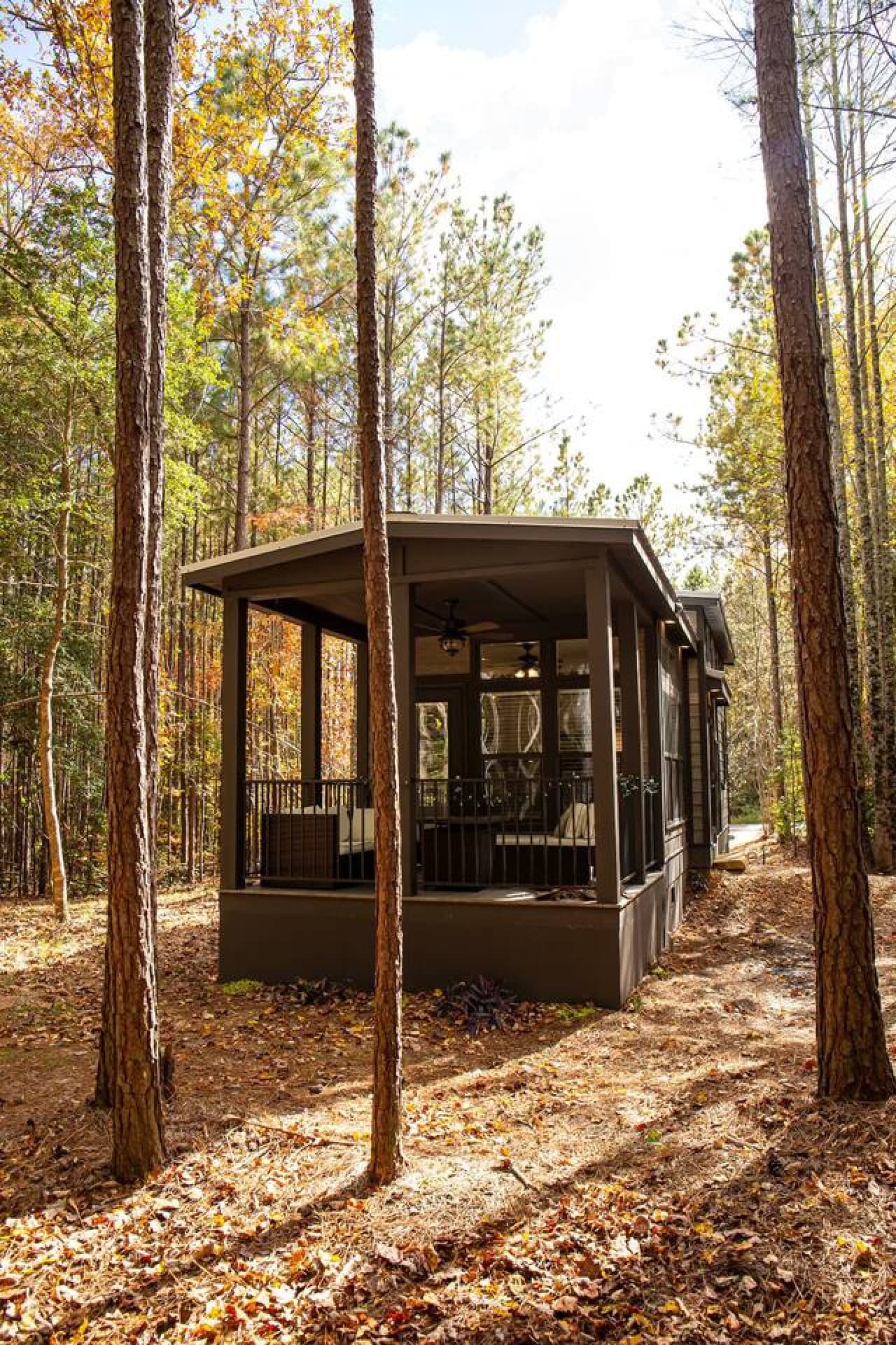 This tiny home, tucked softly into the woods, blends a modern exterior with wide windows that welcome the forest’s natural light.