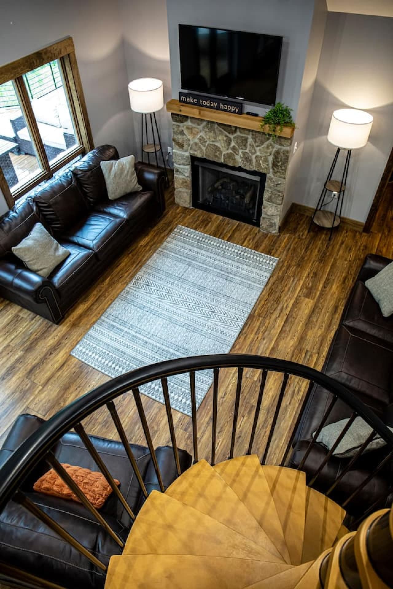 Living room with a stone fireplace, leather sofas, and a spiral staircase leading to the loft.