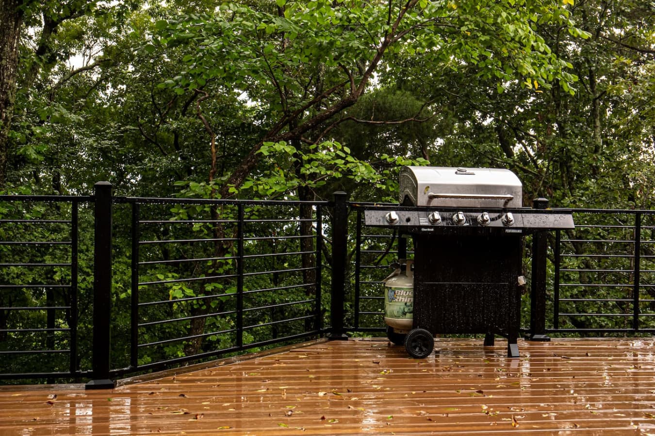 Spacious deck surrounded by trees, featuring a grill—perfect for outdoor cooking and enjoying nature.