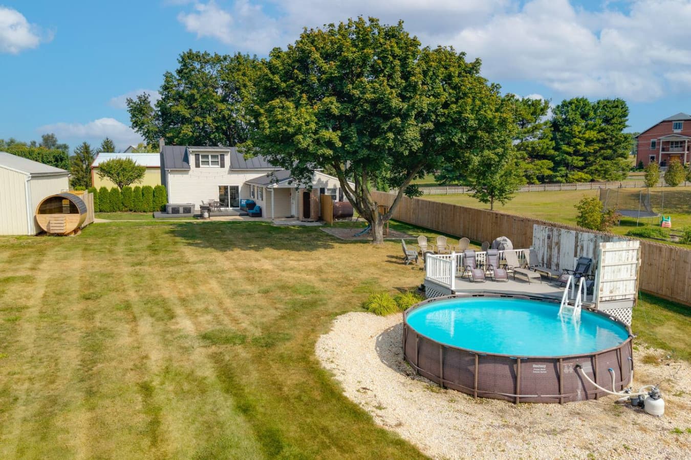 Spacious backyard with pool, lounge area, and large shade tree.