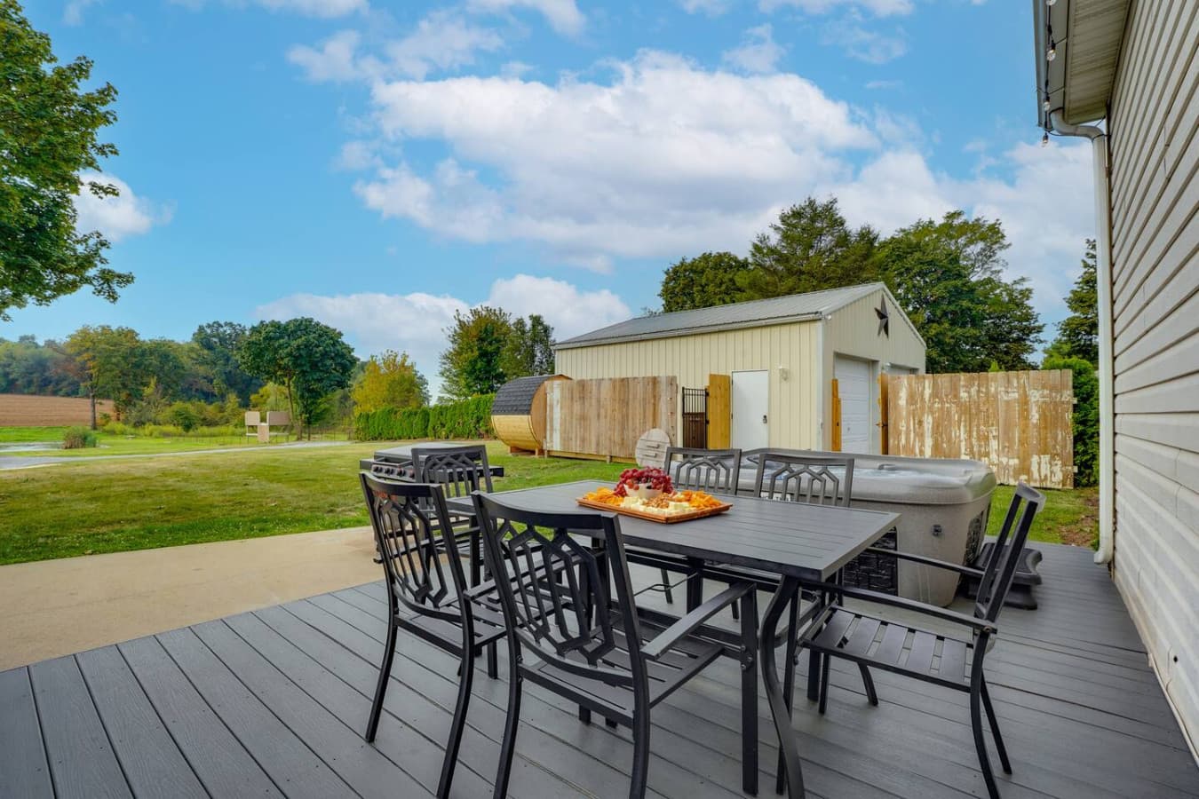 A peaceful outdoor patio with a dining table, greenery, and a shed in the background.