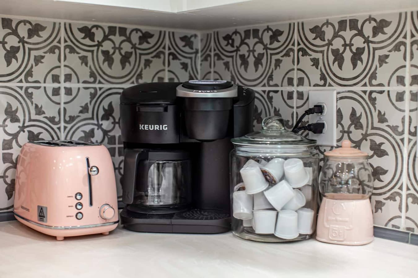 Coffee corner with drip and Keurig coffee makers, a starter kit (2 packs of ground coffee, K-Cups, creamer, sugar), and a toaster.