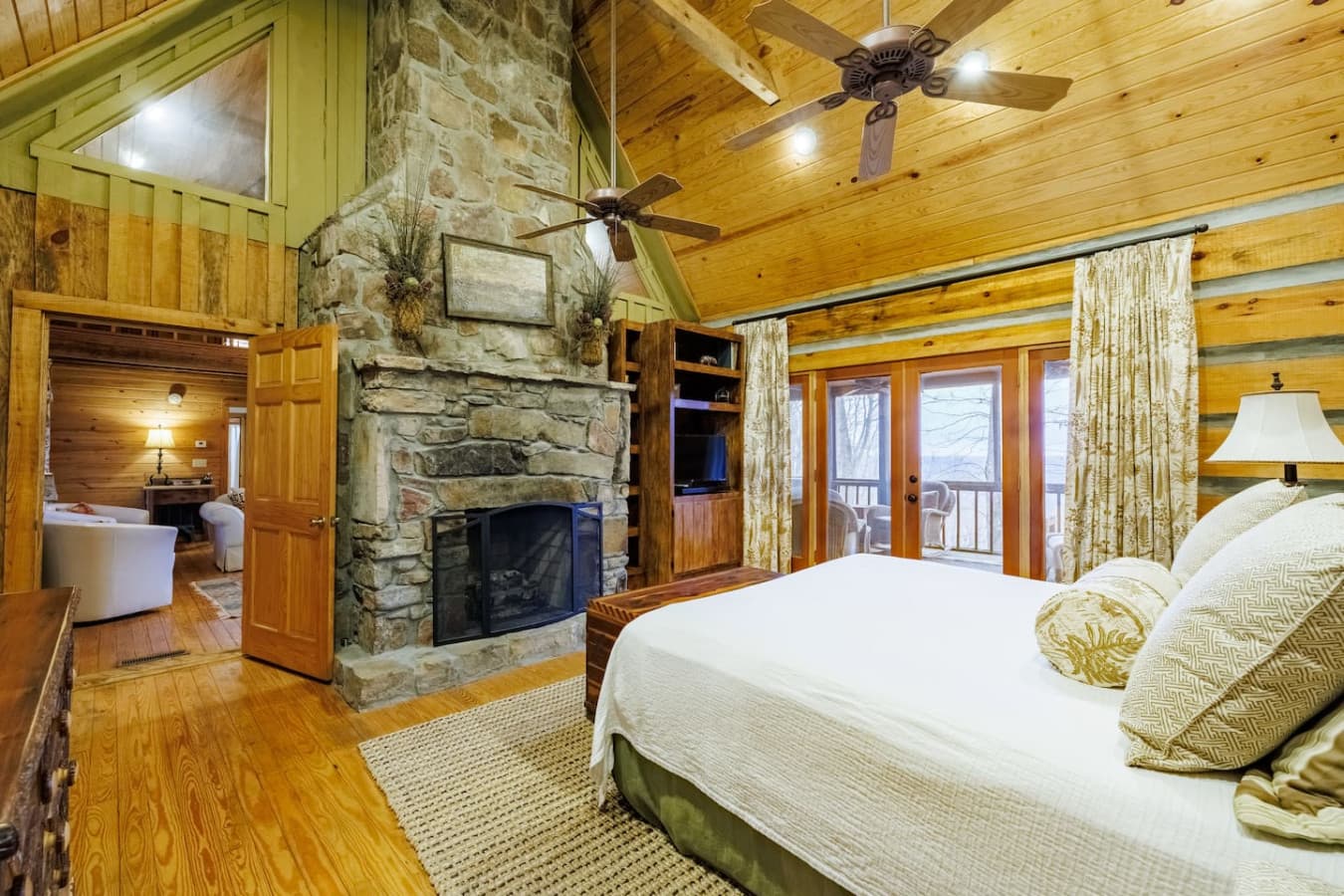 Master bedroom with a private full bathroom and breathtaking mountain, valley, and sunset views. Enjoy a cozy stone gas fireplace, smart TV with cable, and private access to the screened-in porch through sliding glass doors.