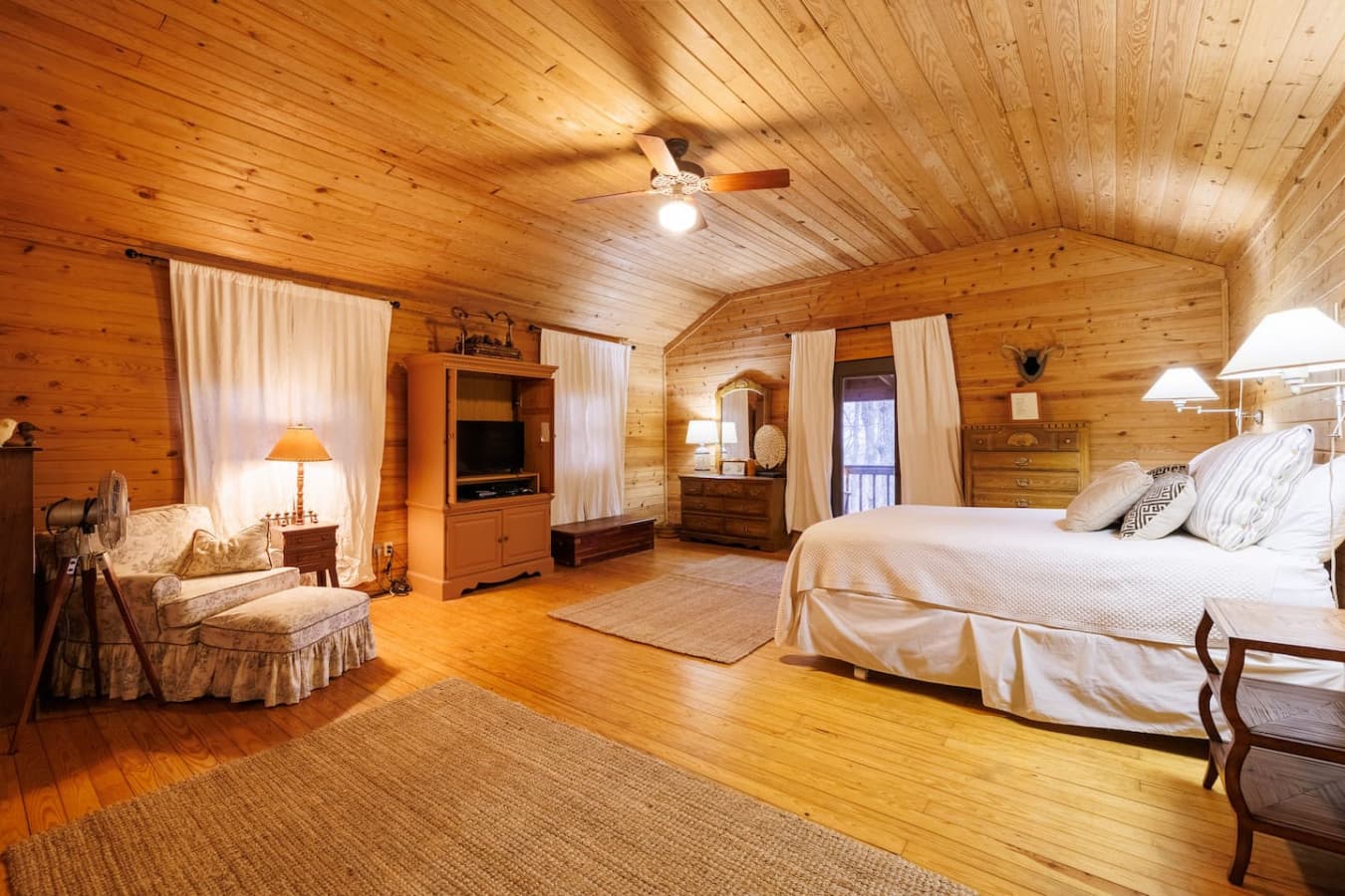 Spacious bedroom with a king bed, cozy wood interiors, and warm natural light. A peaceful retreat for rest and relaxation.