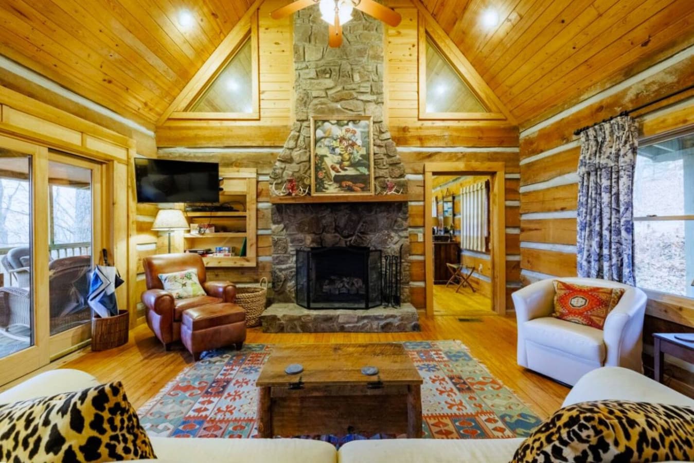 Cozy living room with a stone gas fireplace, stunning mountain and valley views, sliding doors to a screened-in porch, and a smart TV with cable, DVD, and VHS player.