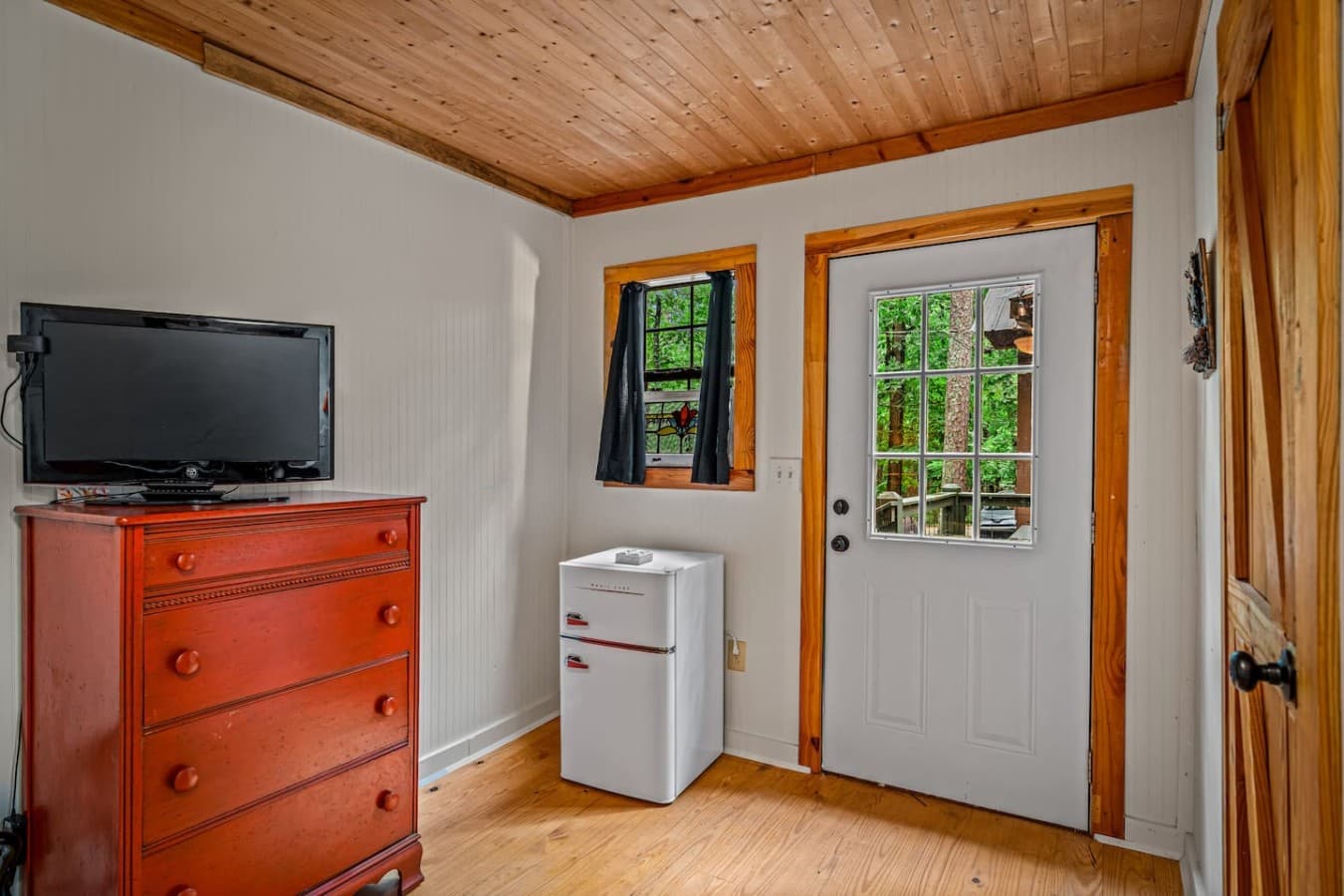 Relax in the Logged Out! room with a smart TV, dresser, and mini fridge.