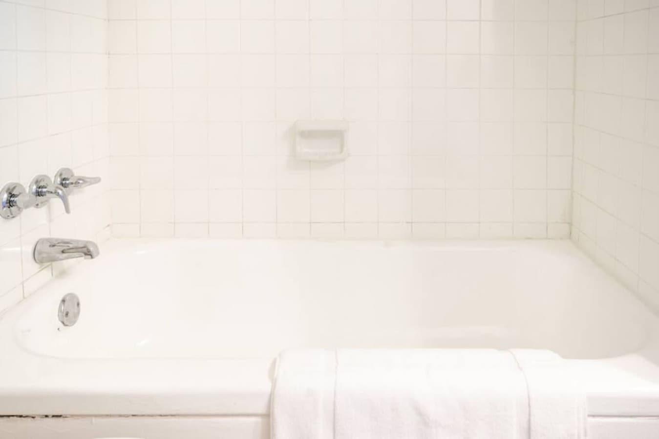 Bright bathroom featuring a bathtub, fresh towels, and simple essentials.