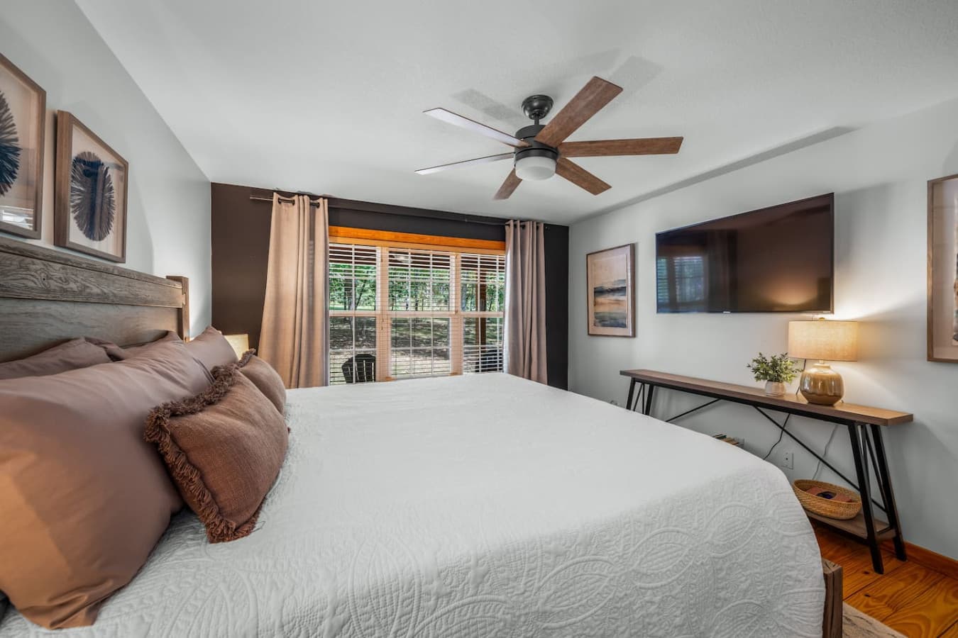 Spacious main floor master bedroom with a king bed, large window, ceiling fan, and Smart TV.