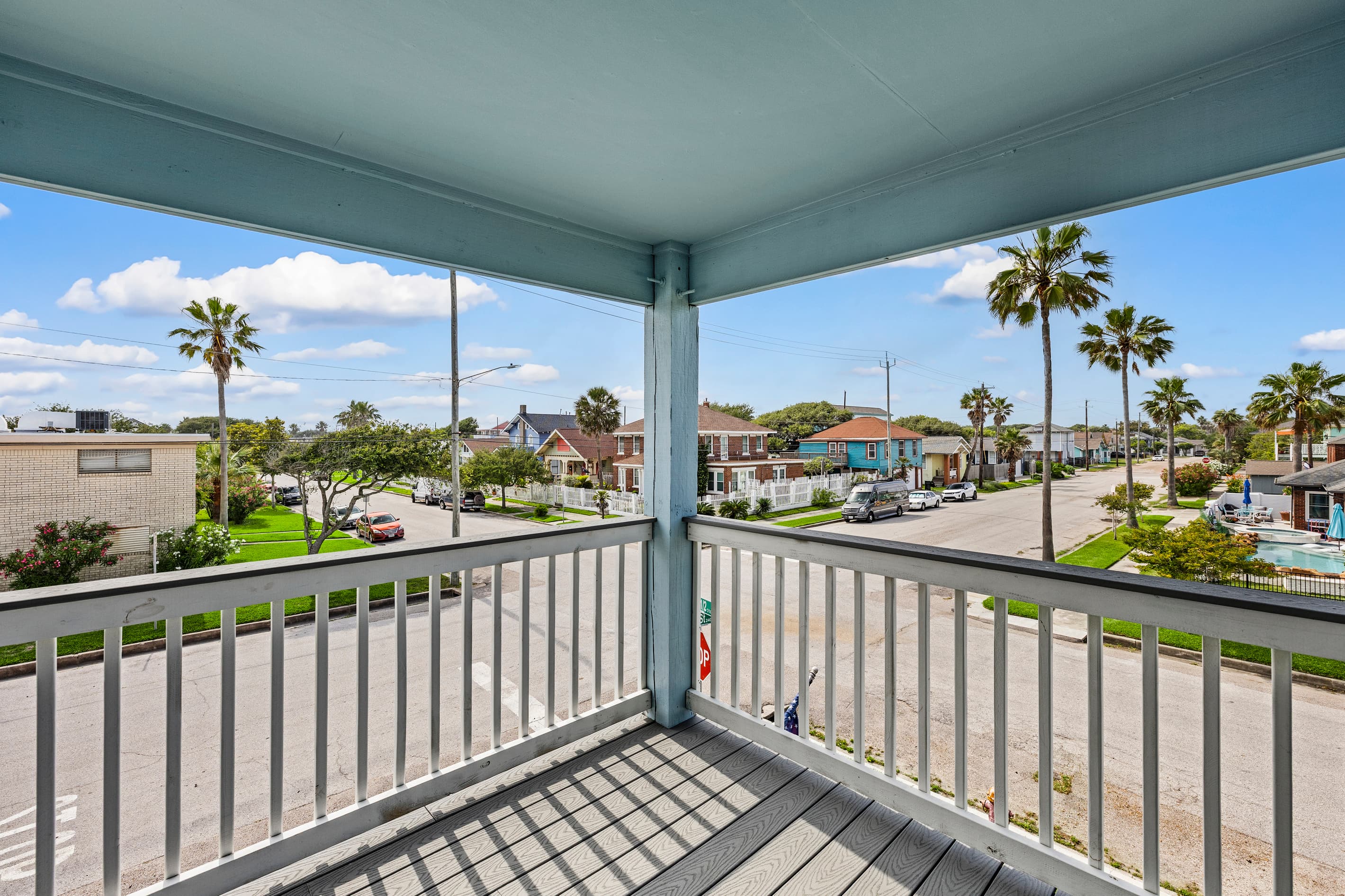 The view from the wraparound deck at The Lookout at R½ — elevated above the neighborhood, palm trees below, Gulf breezes above, and Pleasure Pier within walking distance.
