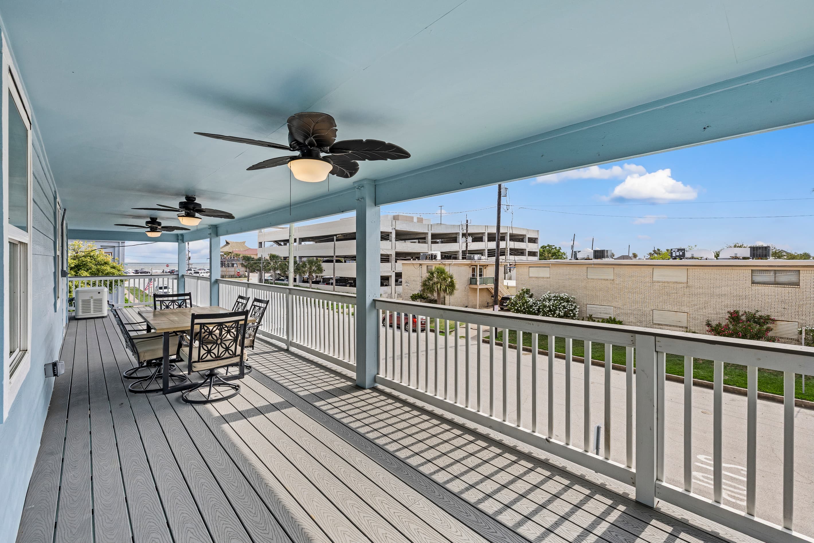 Outdoor dining on the wraparound deck at The Lookout at R½ — table for four with open Gulf views, ceiling fans overhead, and the Galveston Seawall breeze all around.