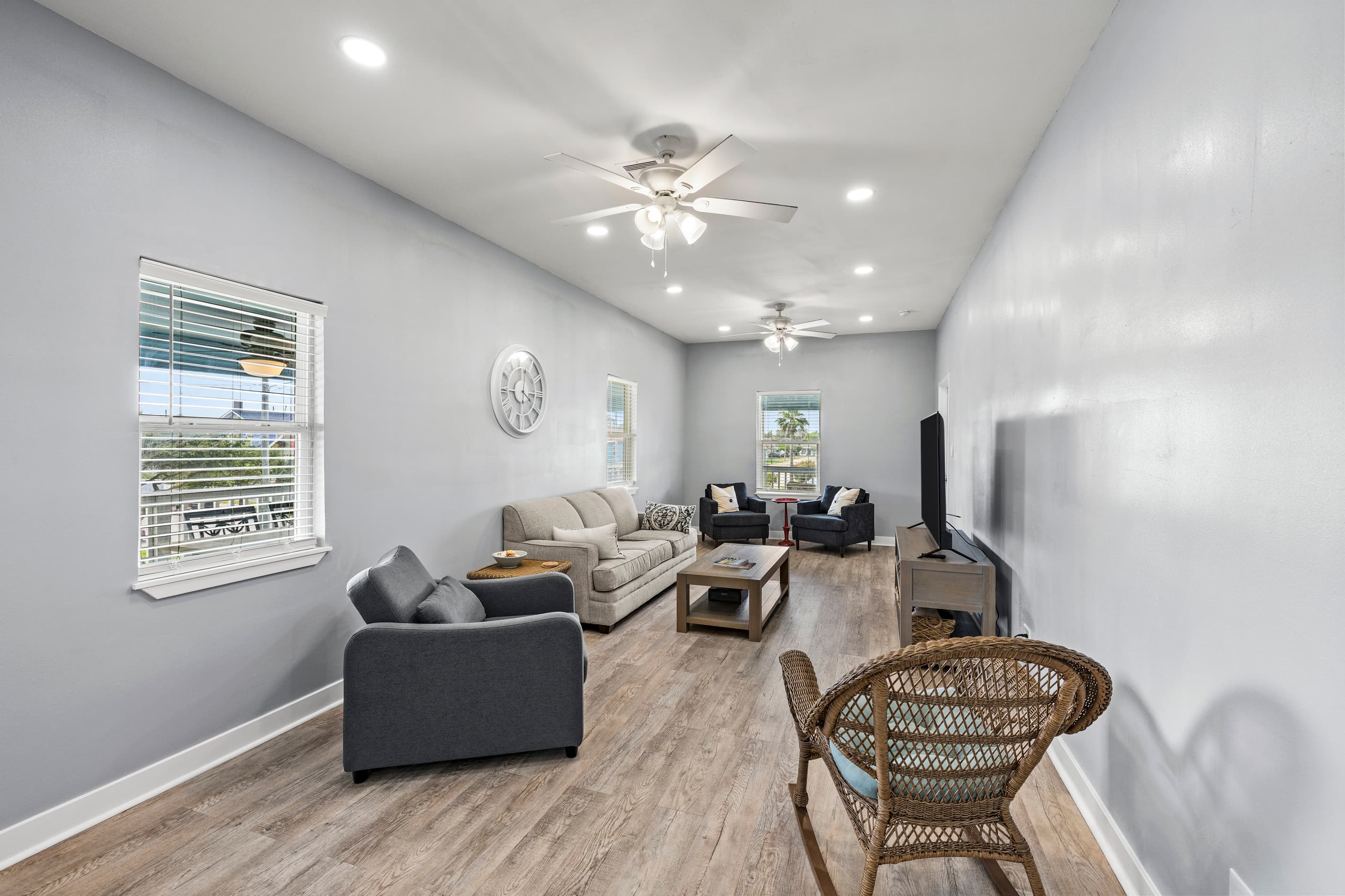 The spacious living room at The Lookout at R½ — full sectional, coffee table, accent chairs, and wraparound windows filling the room with natural Gulf-side light.
