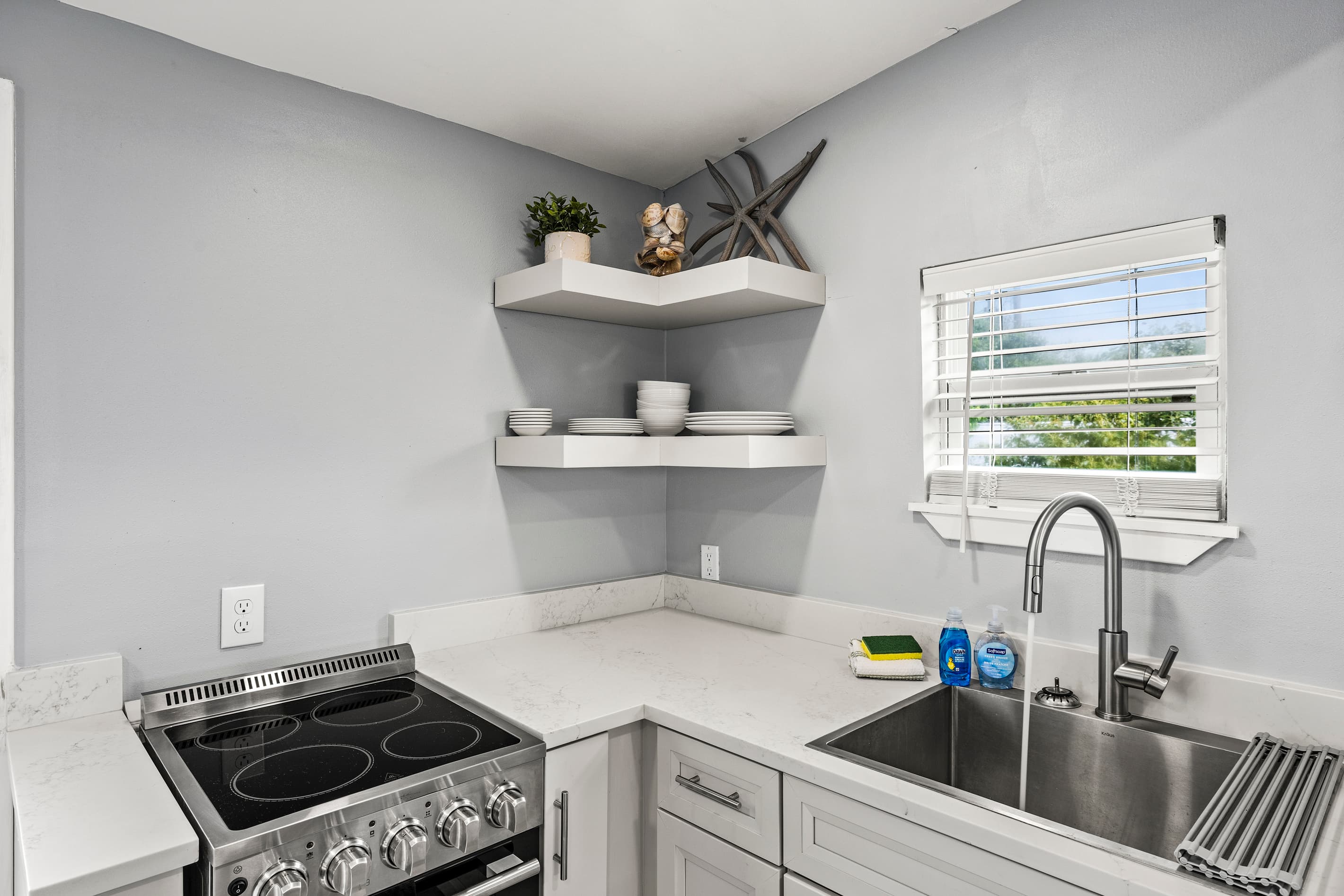Kitchen details at The Lookout at R½ — stainless appliances, modern fixtures, open corner shelving, and generous counter space for cooking real meals on vacation.