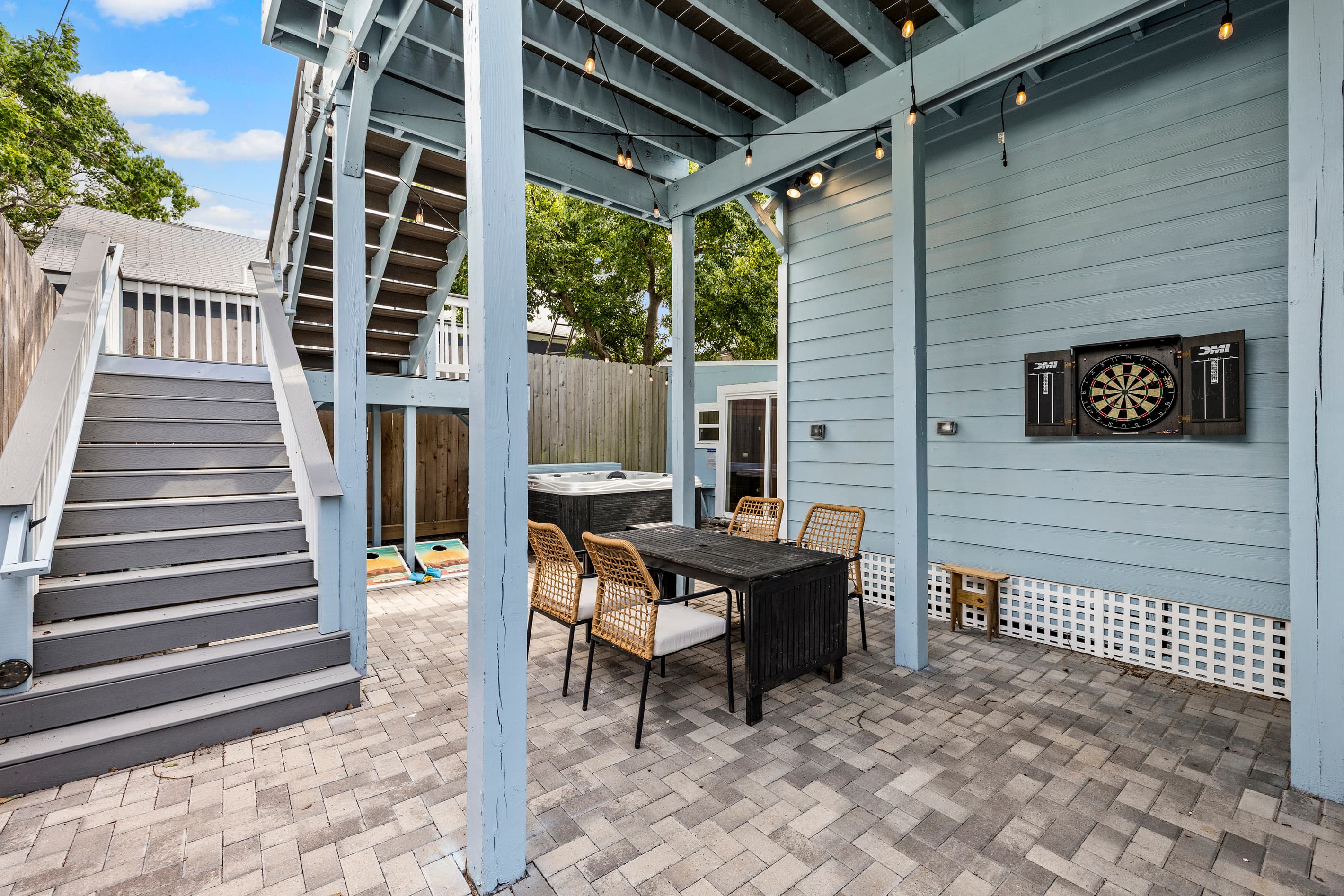 The private courtyard at The Lookout at R½ — a covered pergola with string lights, dartboard, paver patio, and a dining table for four. Outdoor entertaining from morning to midnight.