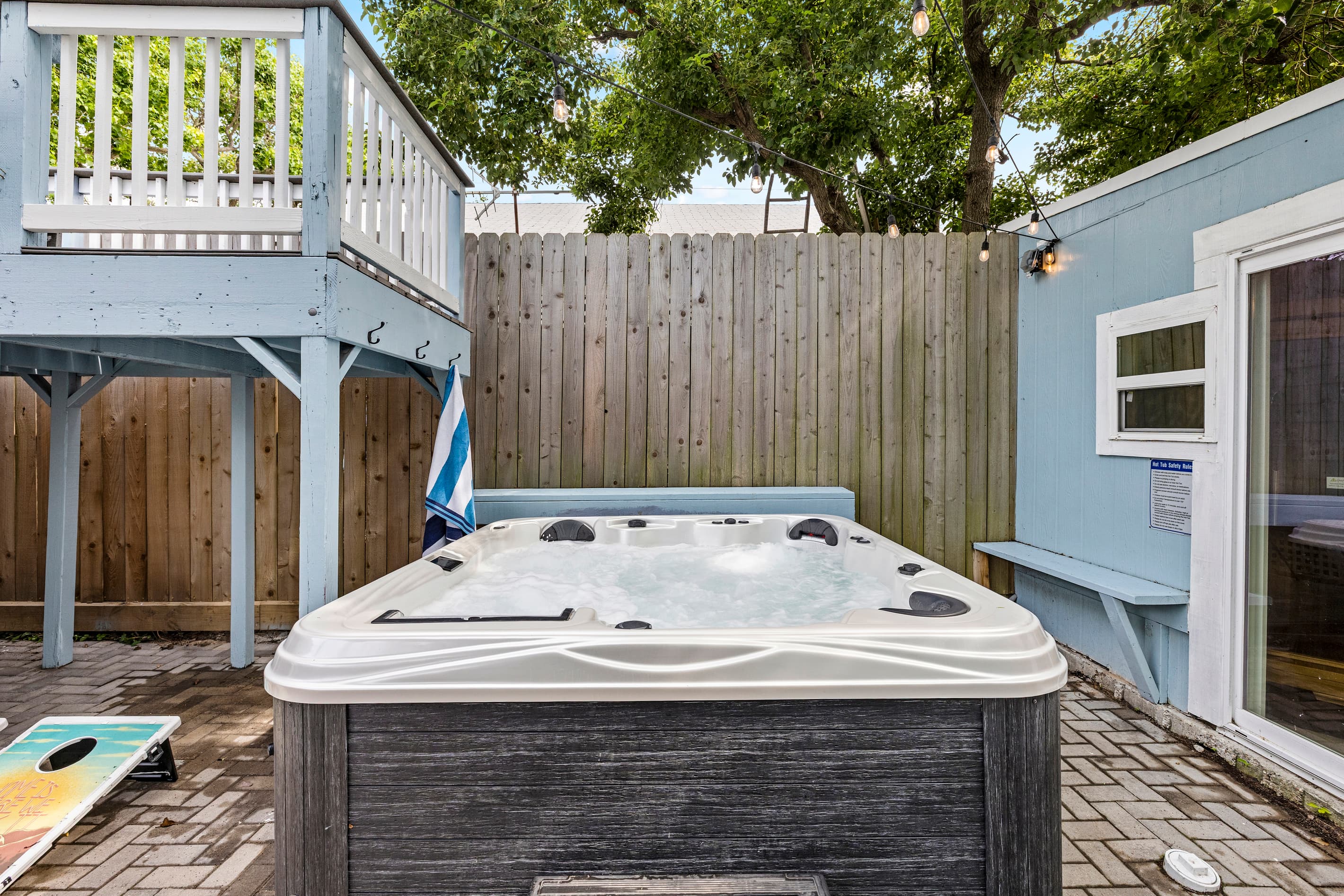 The private hot tub at The Lookout at R½ — soak under the open Galveston sky in the fenced courtyard while the Gulf breeze rolls in. Cornhole and a covered patio steps away.