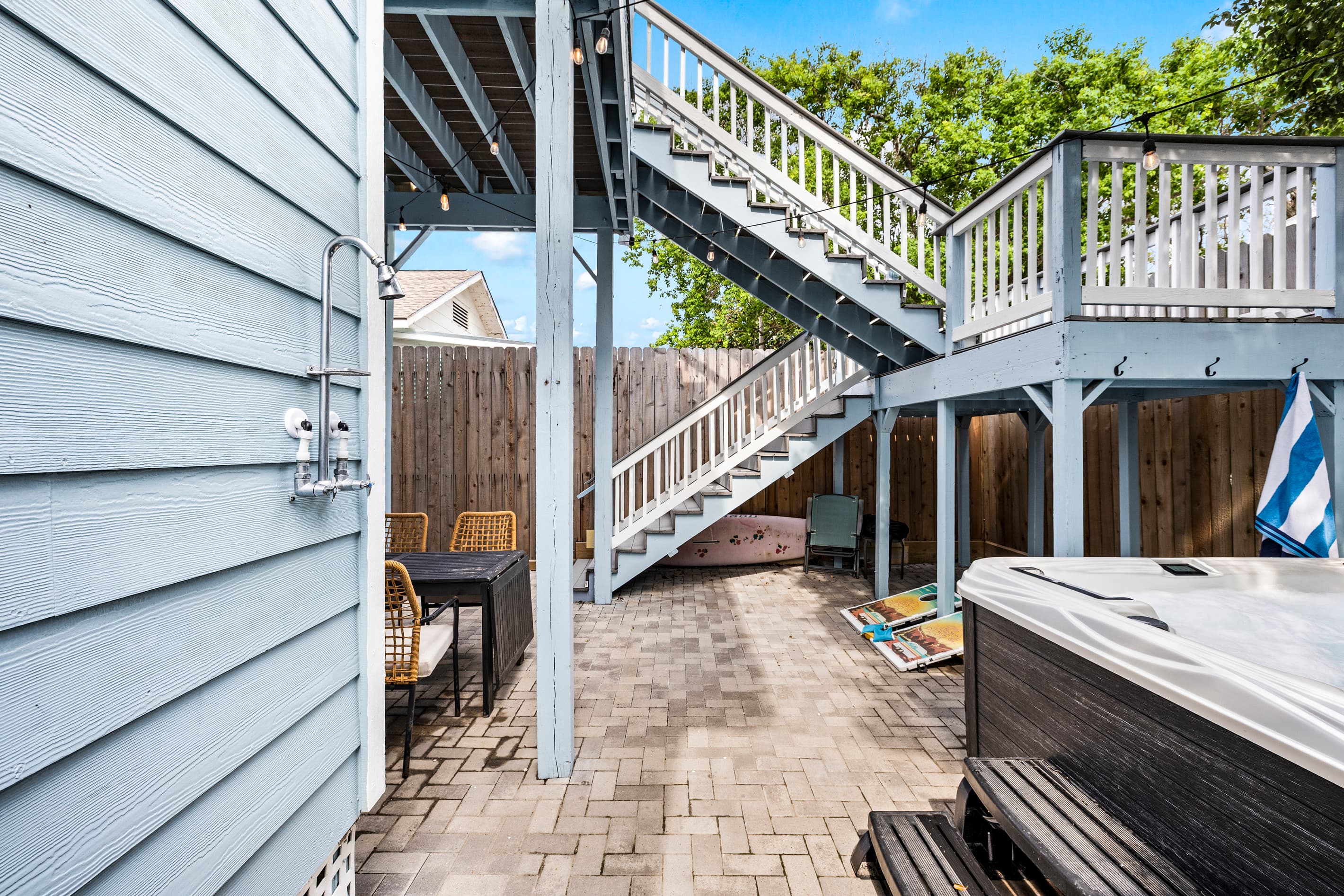 The full private outdoor space at The Lookout at R½ — hot tub, covered pergola, paver courtyard, and the wraparound deck above. An outdoor resort for your group alone.