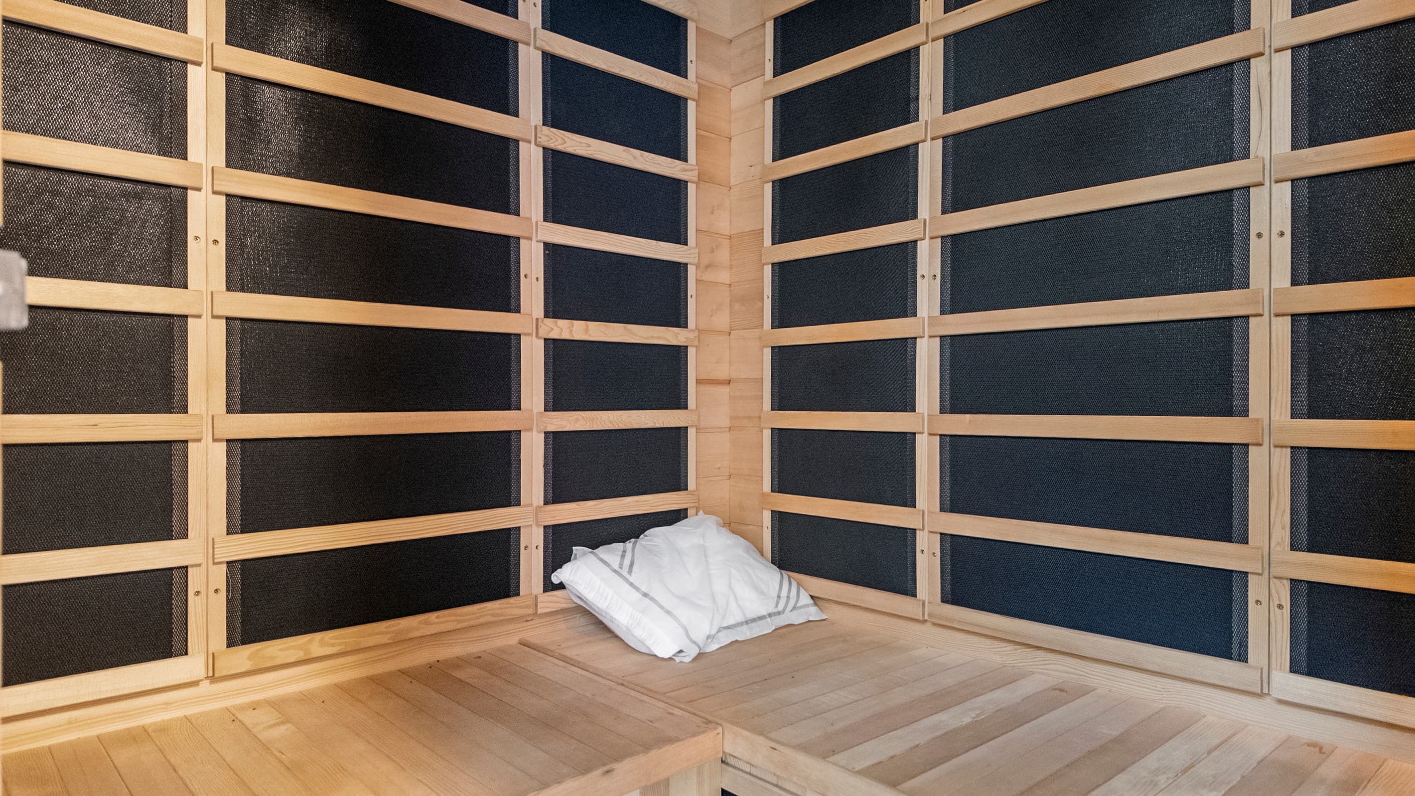 Inside the infrared sauna at The Lookout at R½ — full-panel heating, warm wood detailing, and a cushioned bench. Sweat out the salt air and wake up refreshed every morning.
