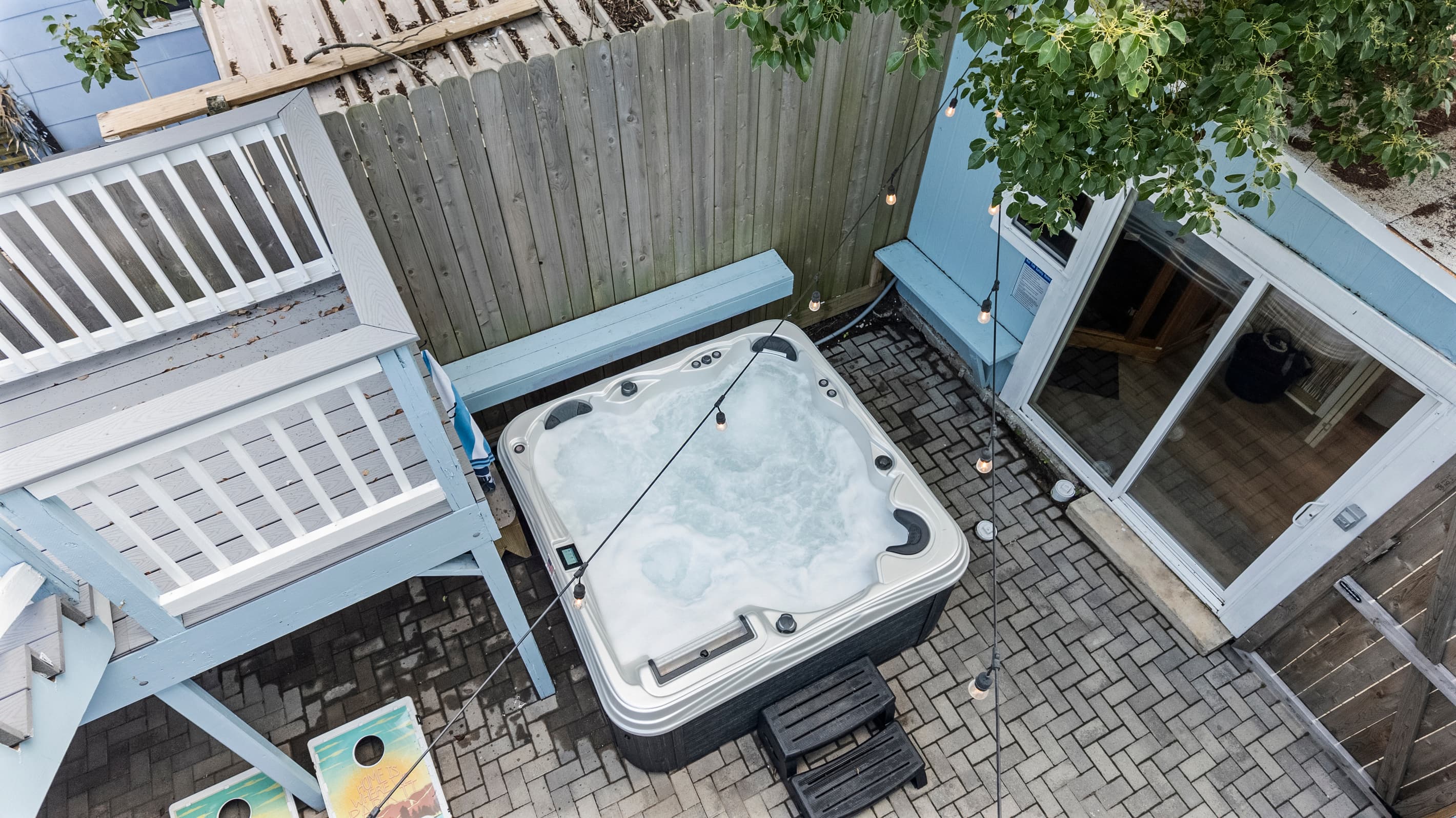 The private courtyard at The Lookout at R½ from above — hot tub below, string lights above, and the wraparound deck overlooking it all. The Lookout lives up to its name.