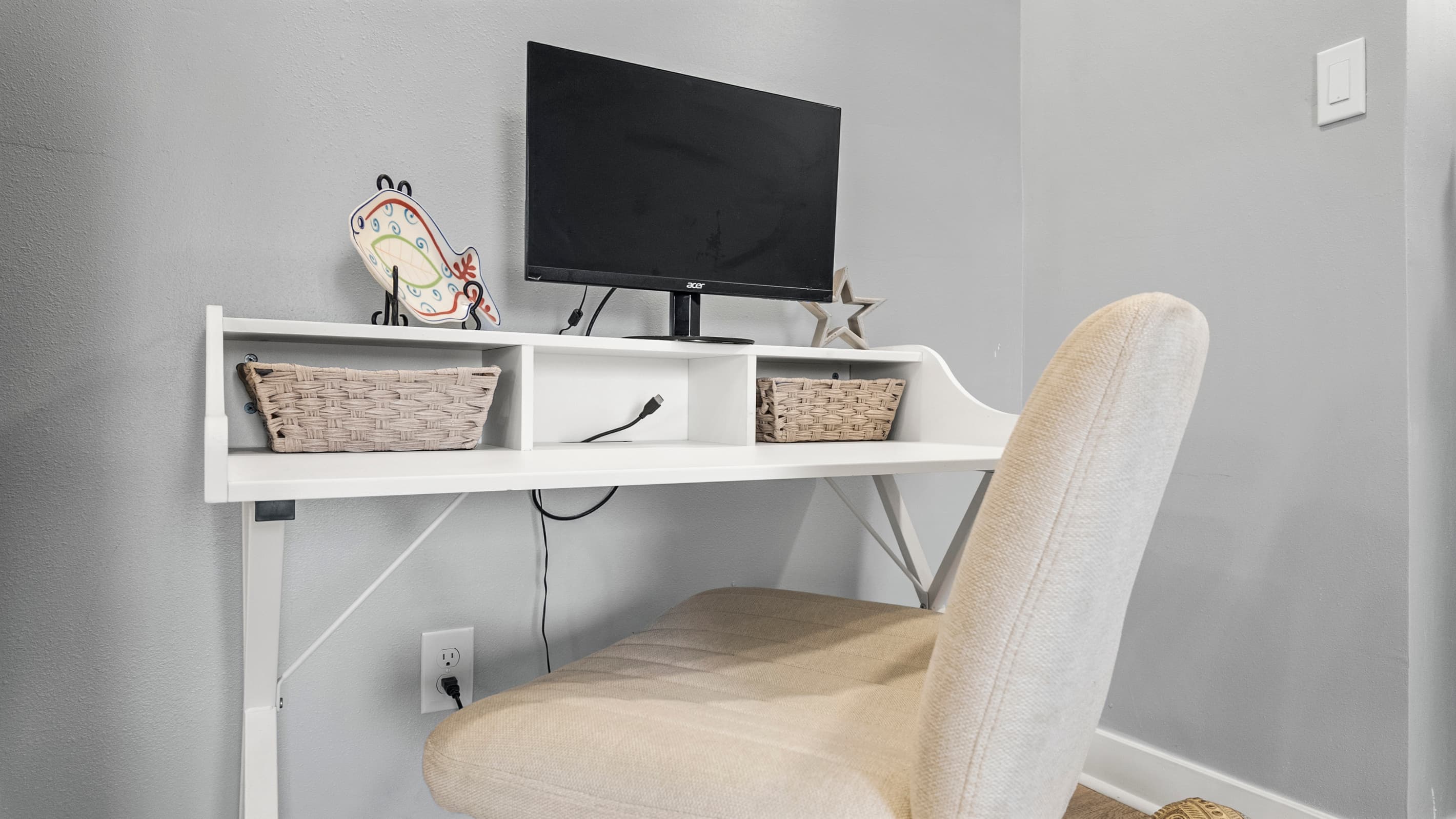 The dedicated workspace at The Lookout at R½ — full desk with monitor, storage baskets, and a comfortable chair. Stay connected without cutting your vacation short.