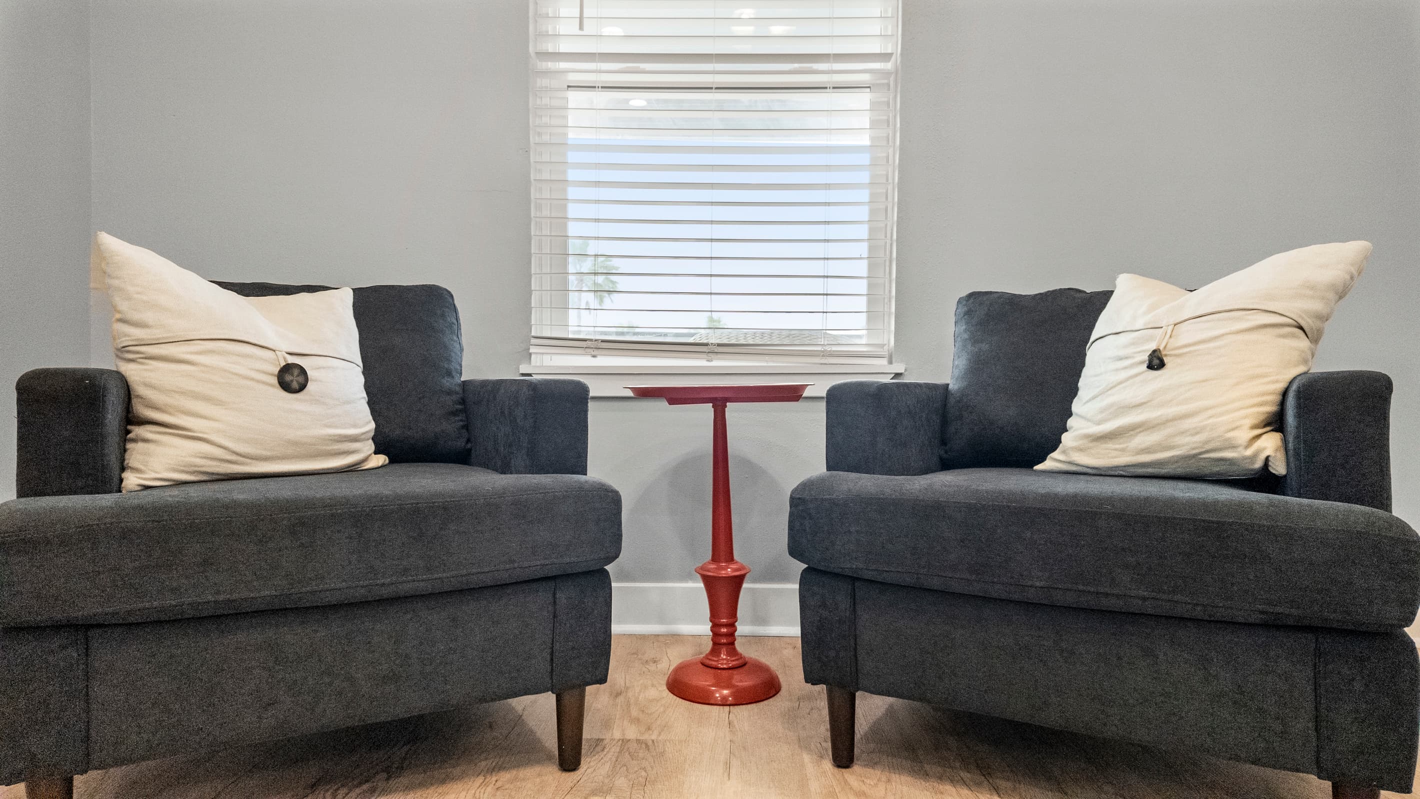 Conversation seating at The Lookout at R½ — two chairs facing each other around a red accent table. The perfect spot for morning coffee or an evening catch-up.