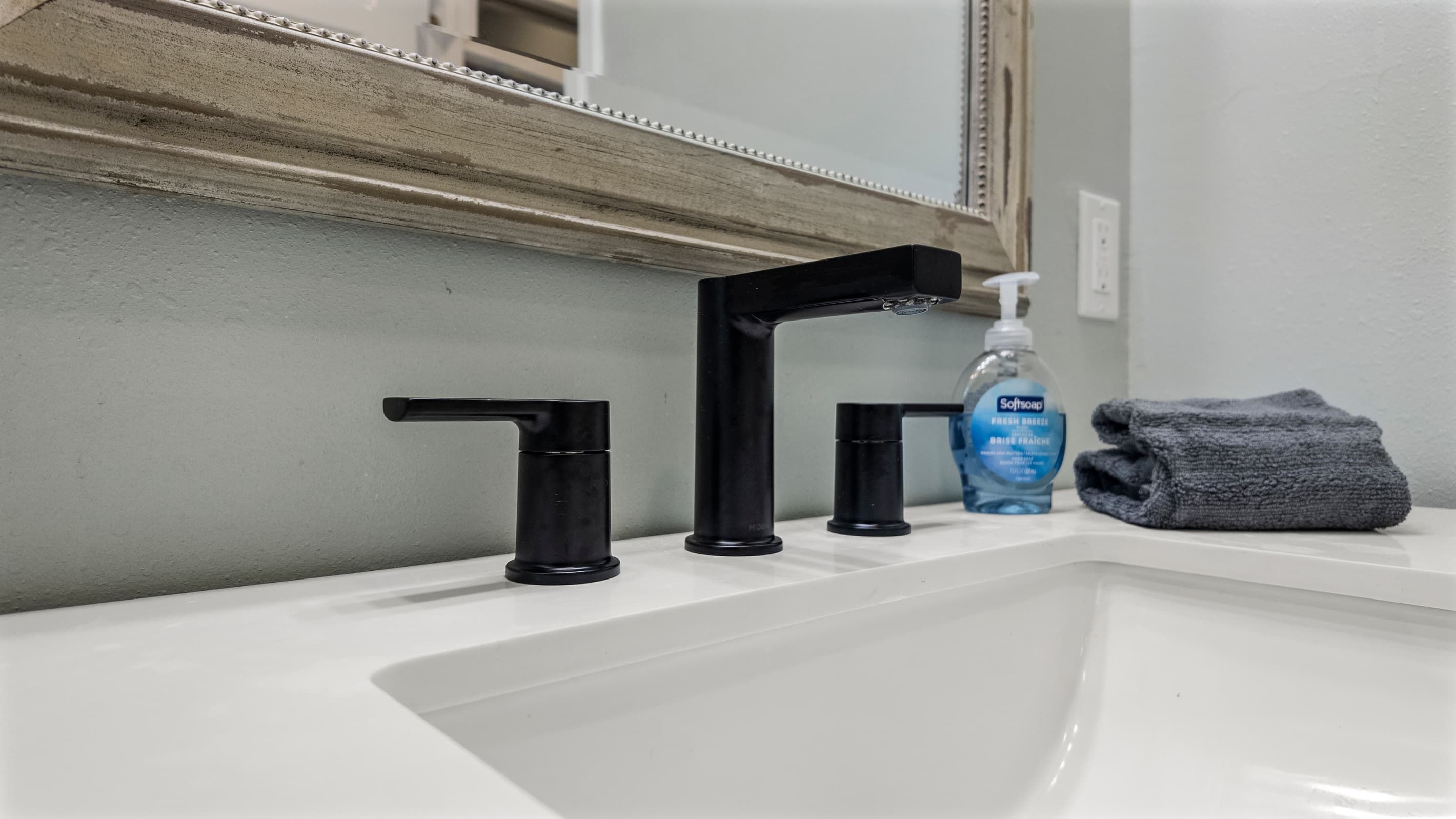 Bathroom details at The Lookout at R½ — matte black faucet, undermount sink, framed mirror, and fresh towels provided. A clean, elevated finish throughout.