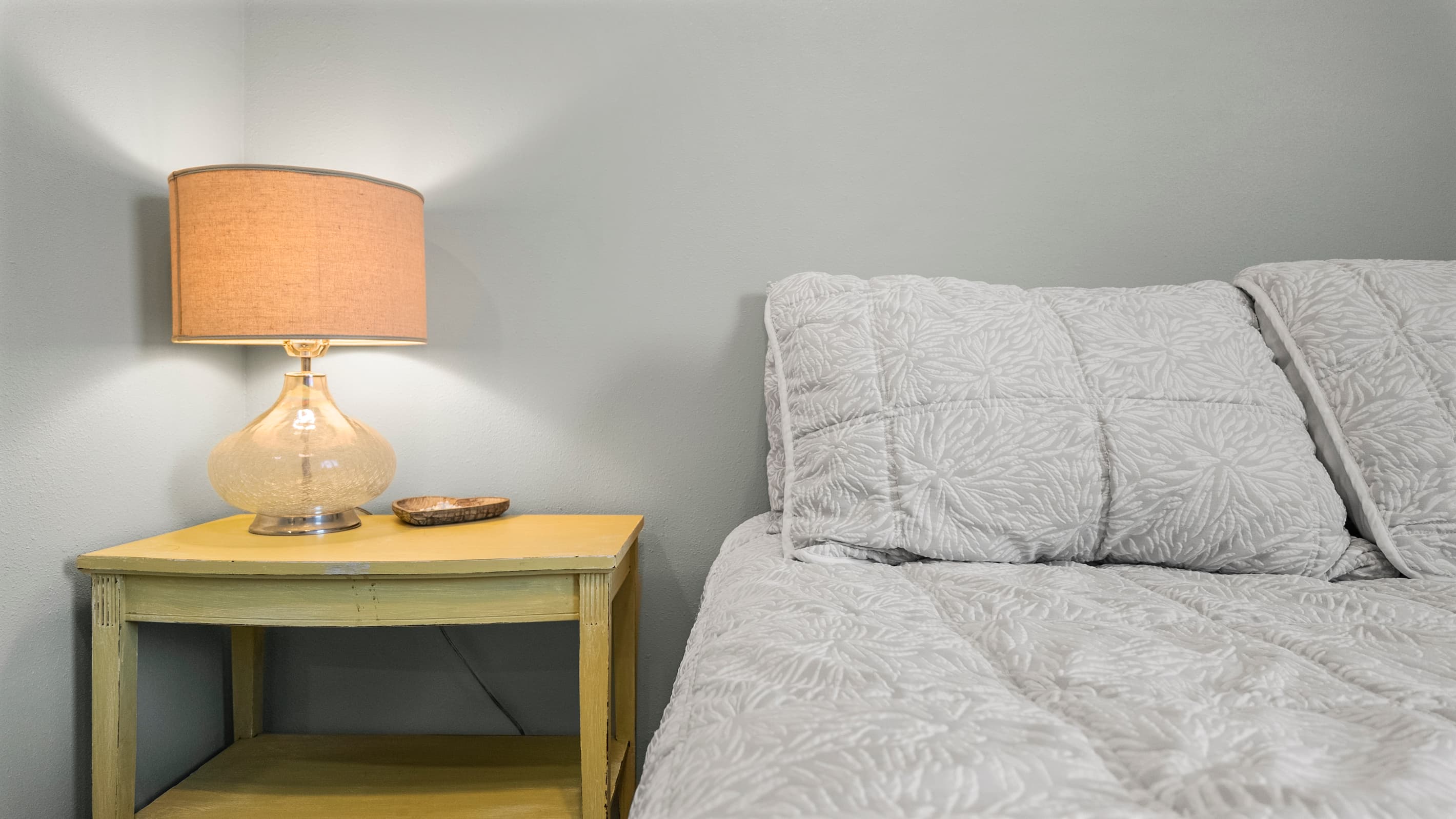 Bedside details at The Lookout at R½ — a warm amber lamp and wooden nightstand. The small touches that make a vacation rental feel like a home away from home.