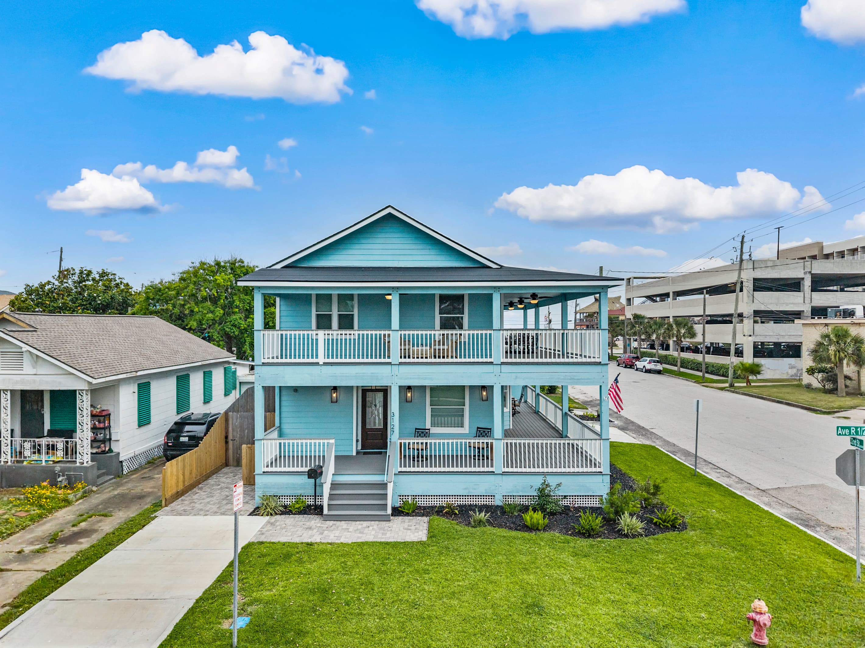 The front entrance at The Lookout at R½ — a welcoming wraparound porch, fresh landscaping, and keypad entry for seamless self check-in. Your Galveston home base starts here.
