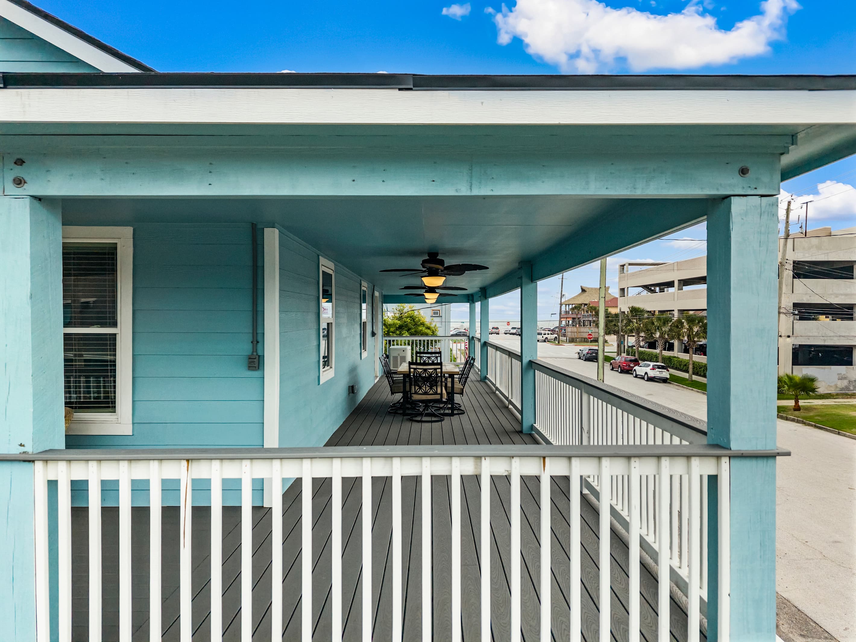 The upper wraparound deck at The Lookout at R½ — a ceiling fan, rocking chair, and an open view toward the Galveston Seawall. Step outside from the main living area and settle in.