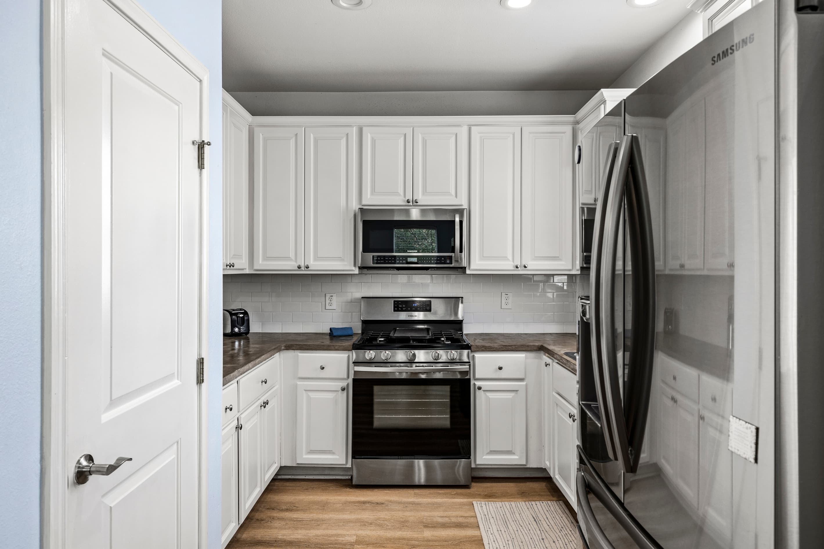 The fully equipped kitchen at Summer Bliss — white cabinets, stainless gas range, microwave, and a full-size fridge. Everything needed for group meals or quick beach snacks.