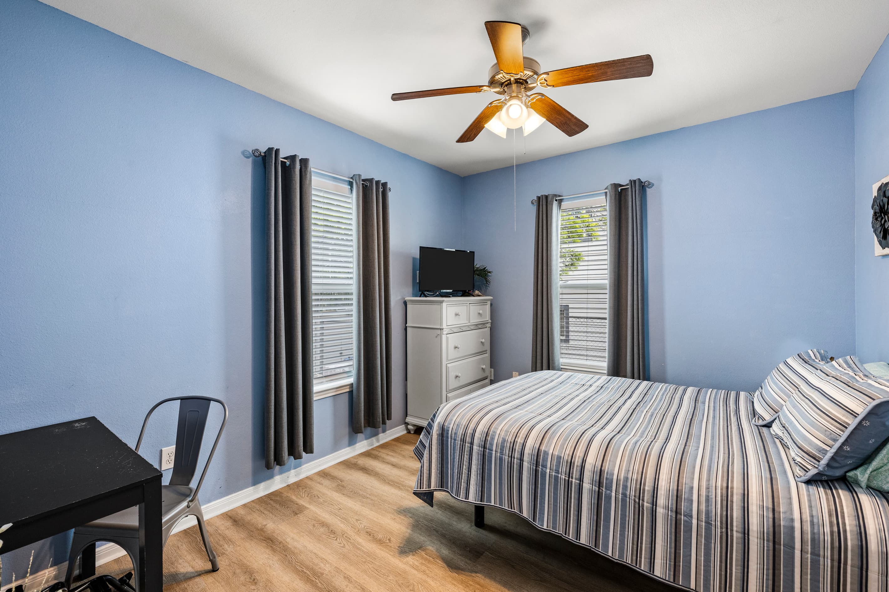 The master suite at Summer Bliss — a queen bed, ceiling fan, smart TV, and a dedicated desk on the main level with no stairs required. Private and comfortable for the whole stay.