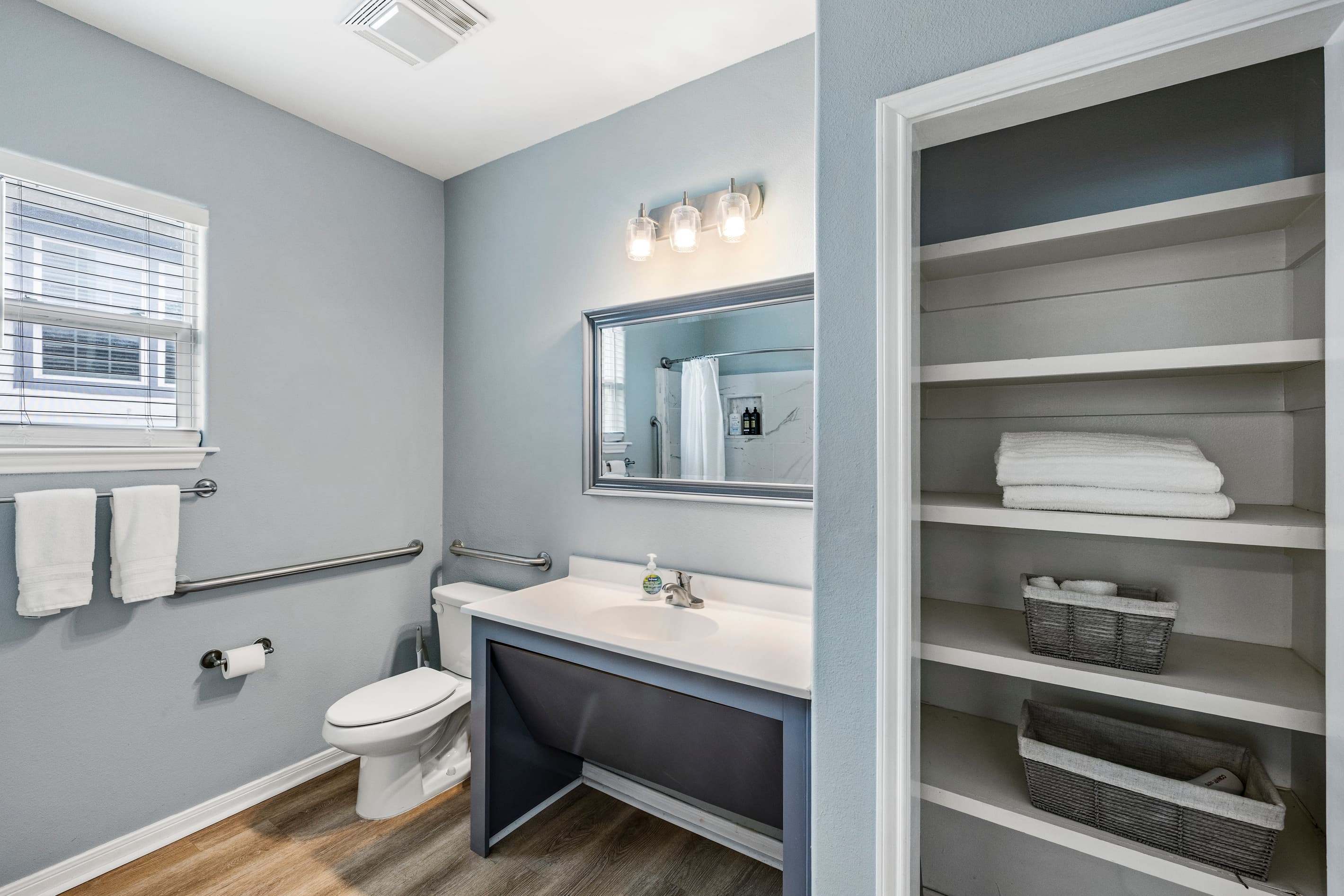 The master en-suite bathroom at Summer Bliss — vanity sink, built-in shelving stocked with fresh towels, and a private entrance directly from the master suite.