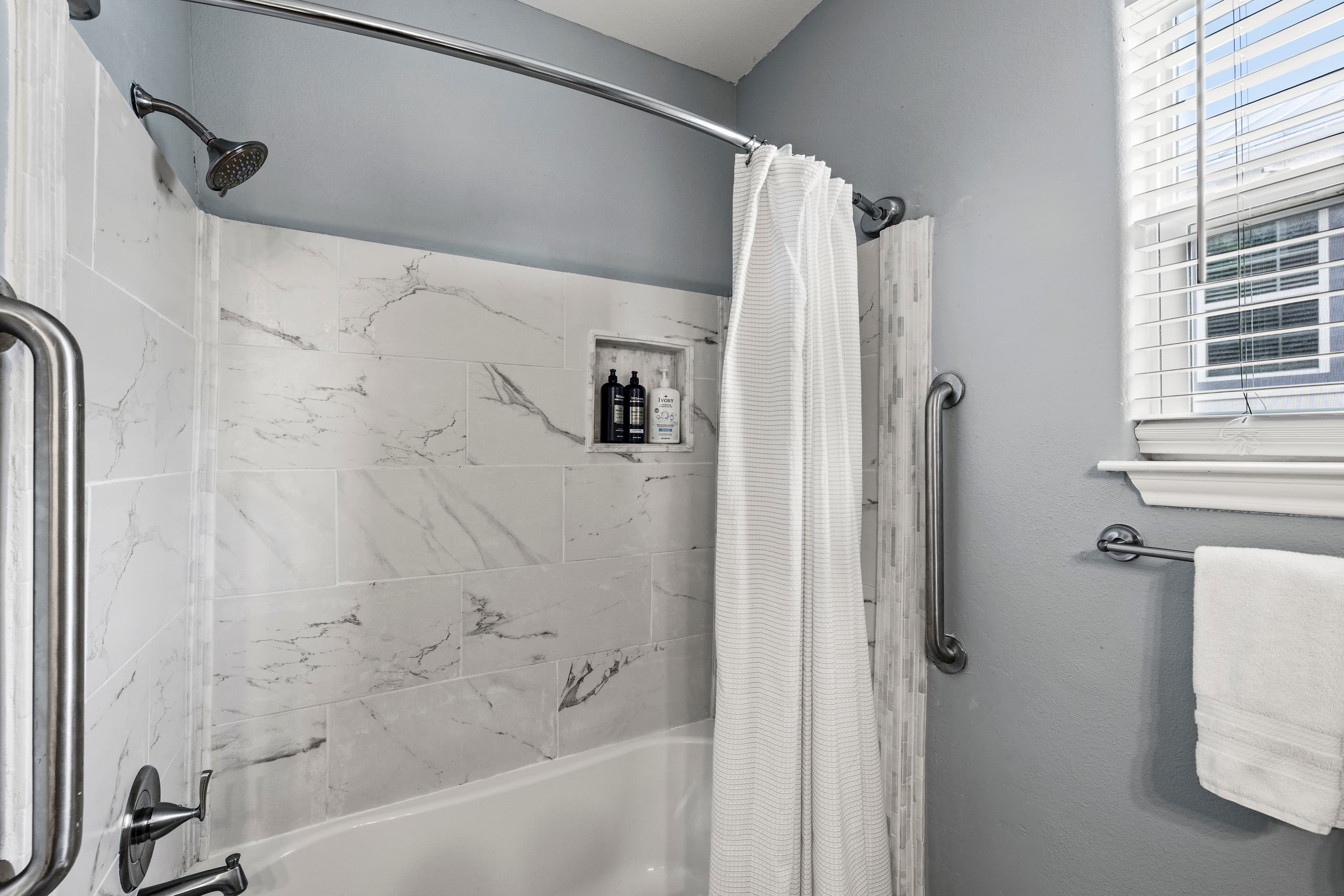 The master bathroom shower and tub at Summer Bliss — marble-look tile, full tub/shower combination, and private access from the main-level master suite.