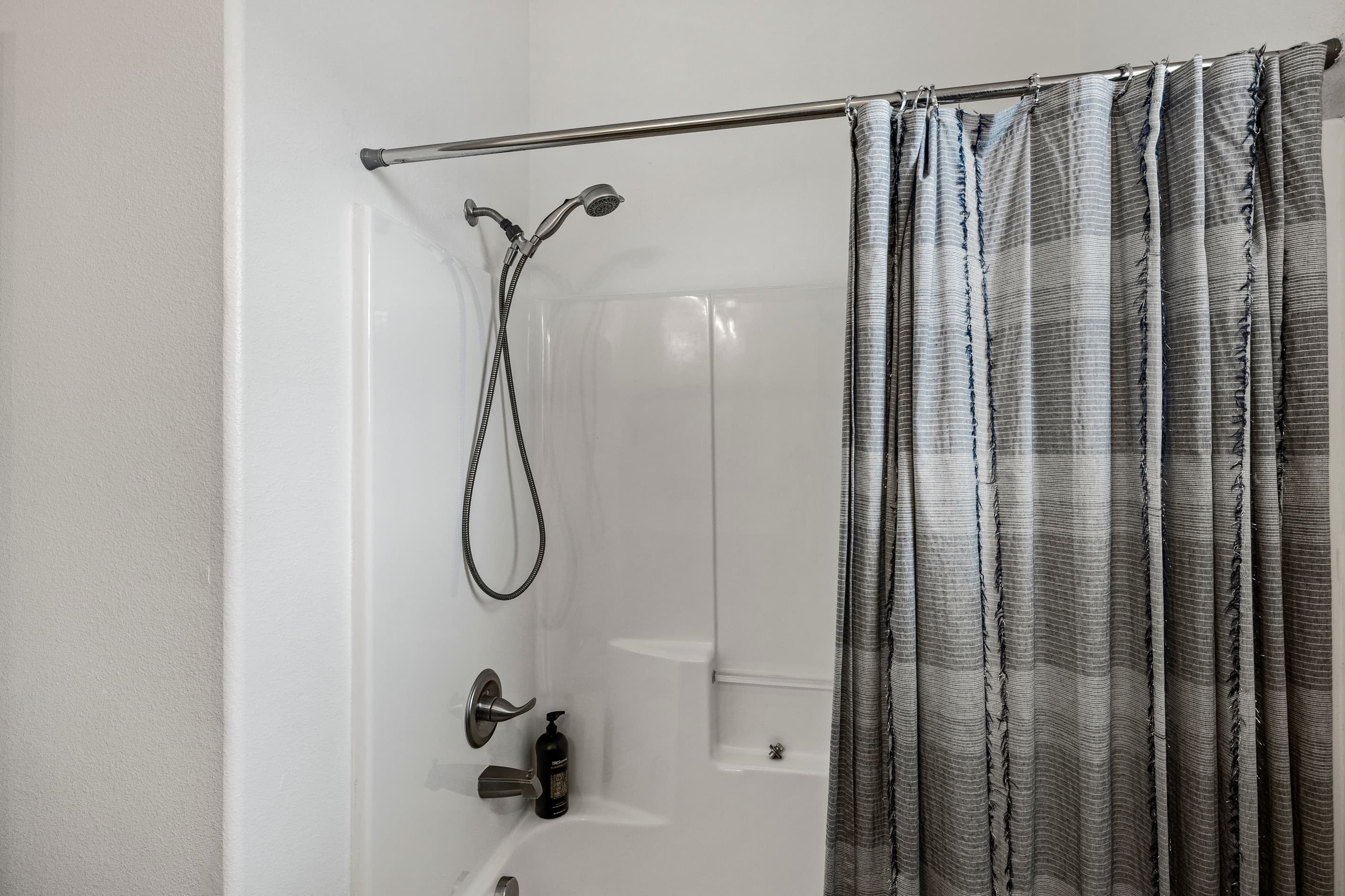 The upstairs shower at Summer Bliss — clean white tile, full tub and shower combo, and everything needed for rinsing off after a day at the beach.