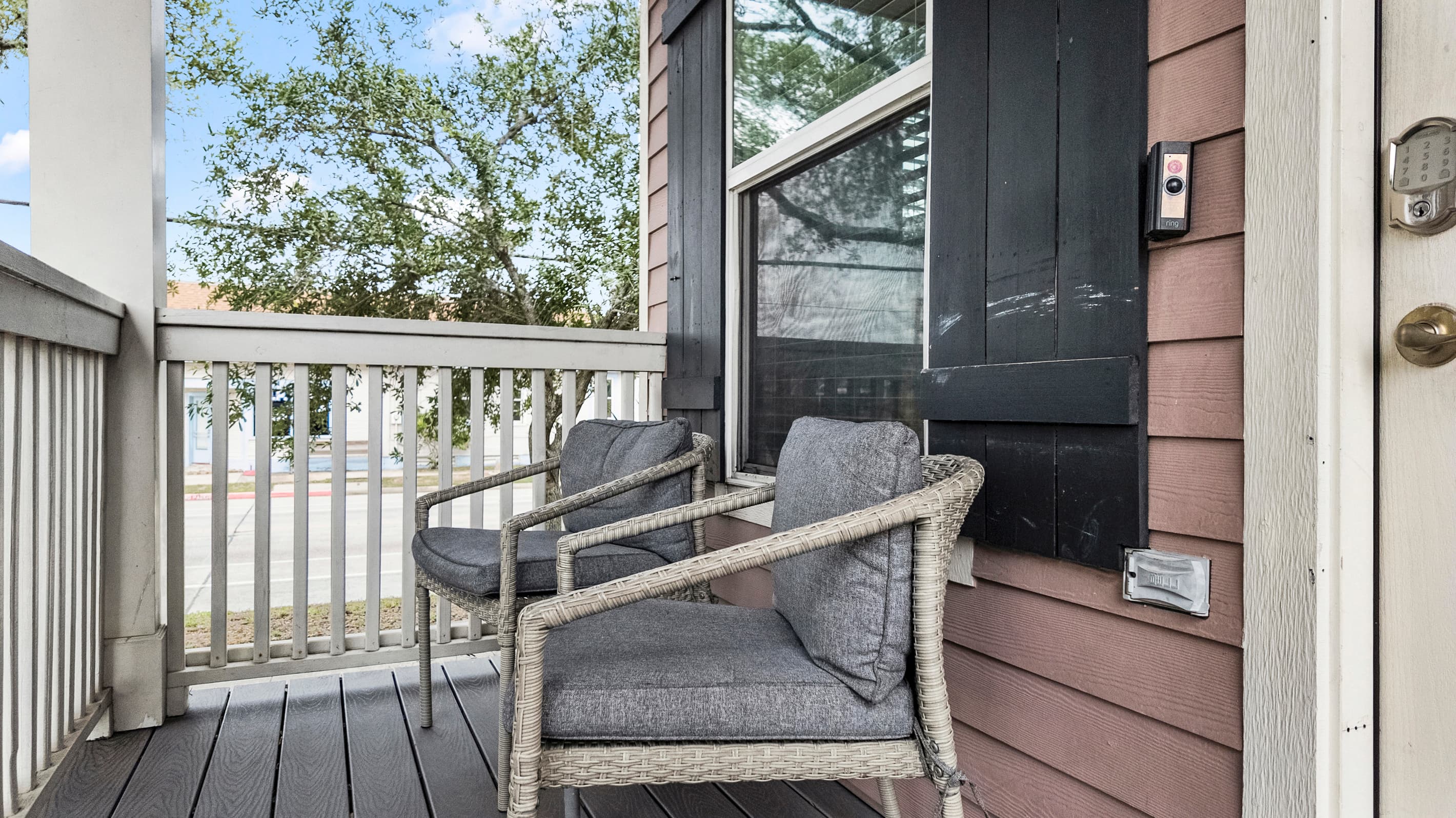 The covered front porch at Summer Bliss — wicker seating above the corner lot. A perfect spot for morning coffee before heading to the beach.