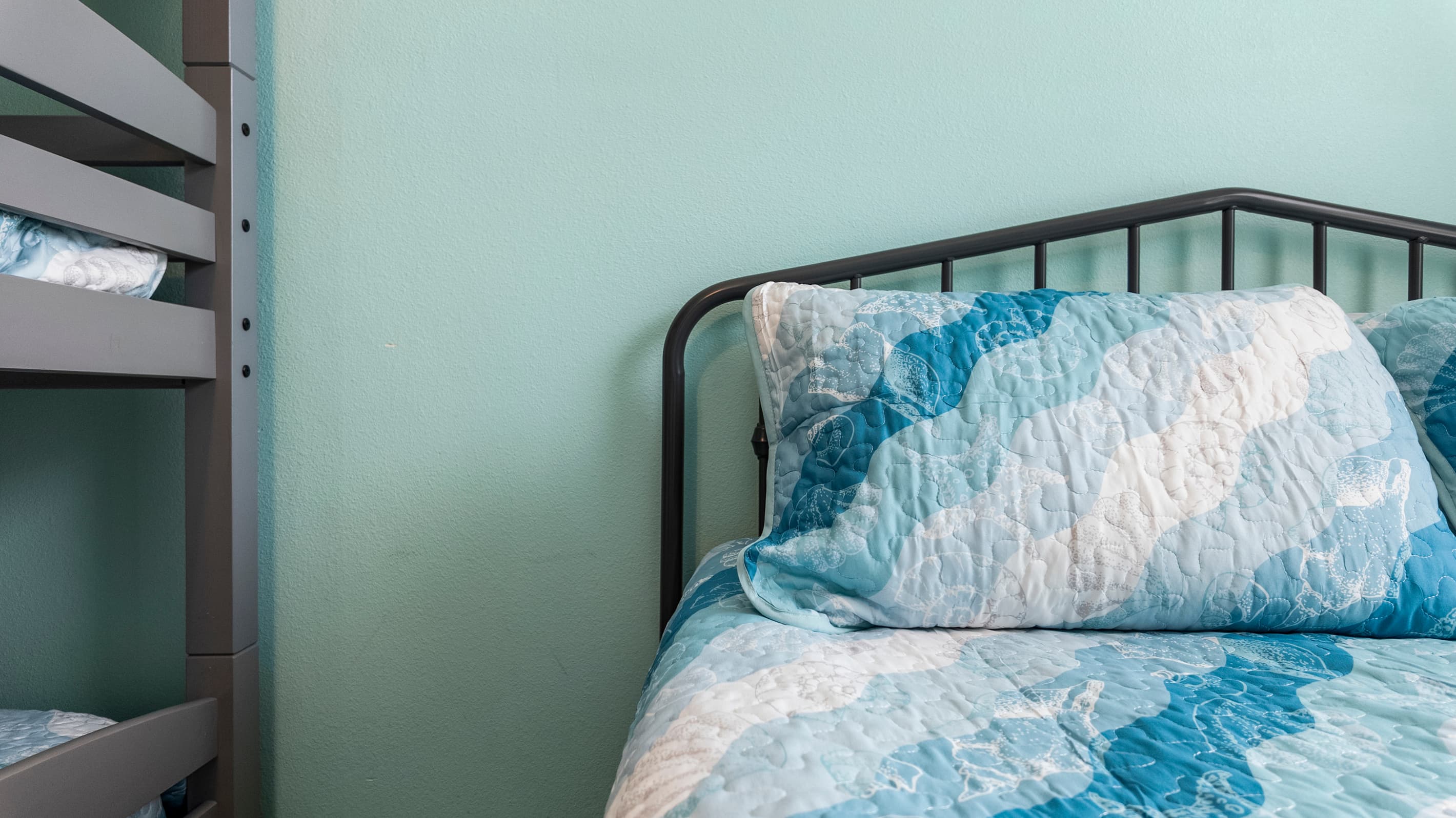 The queen bed in Bedroom 3 at Summer Bliss — ocean-themed bedding and a comfortable retreat alongside the bunk beds. Plenty of sleeping options for the whole group.