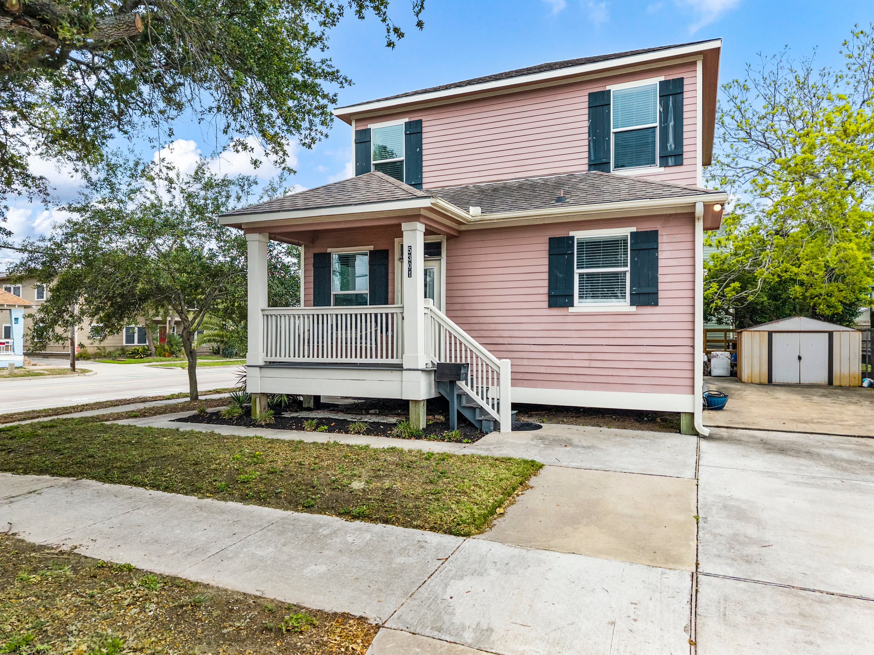 Another view of Summer Bliss — the covered porch, corner lot, and lush tree canopy that frames the property. Charming from every angle.
