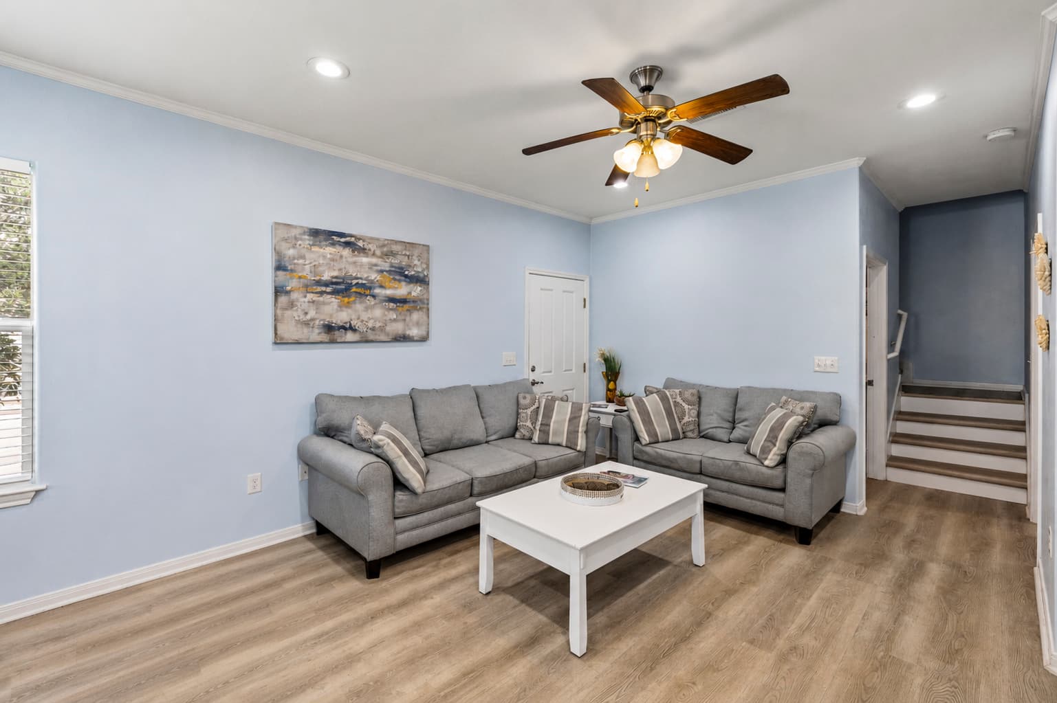 Another angle of the living room at Summer Bliss — gray sectional sofa, white coffee table, and natural light throughout. A welcoming space for the whole group.