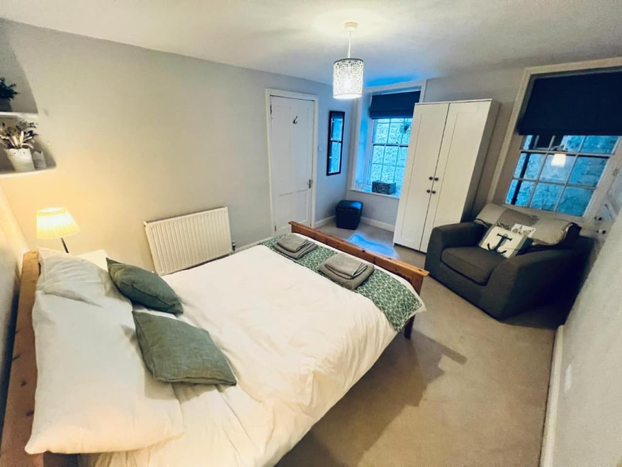 Bedroom 1 - double bed, patterned cushions, armchair, two windows (angle 2)