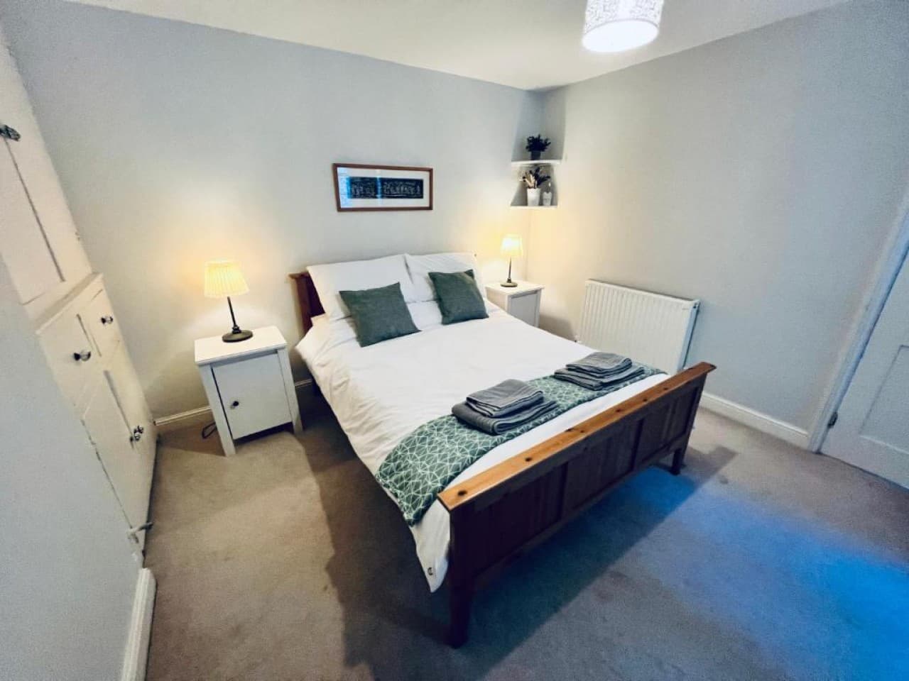 Bedroom 1 - double bed, green throw, bedside lamps, wardrobe (angle 1)